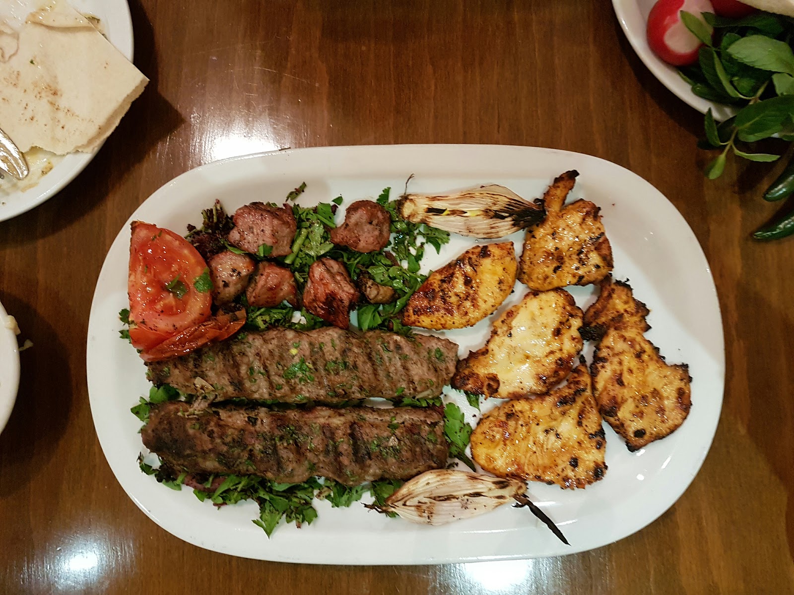 A mixed grill platter of kebab and tawouk with grilled tomato