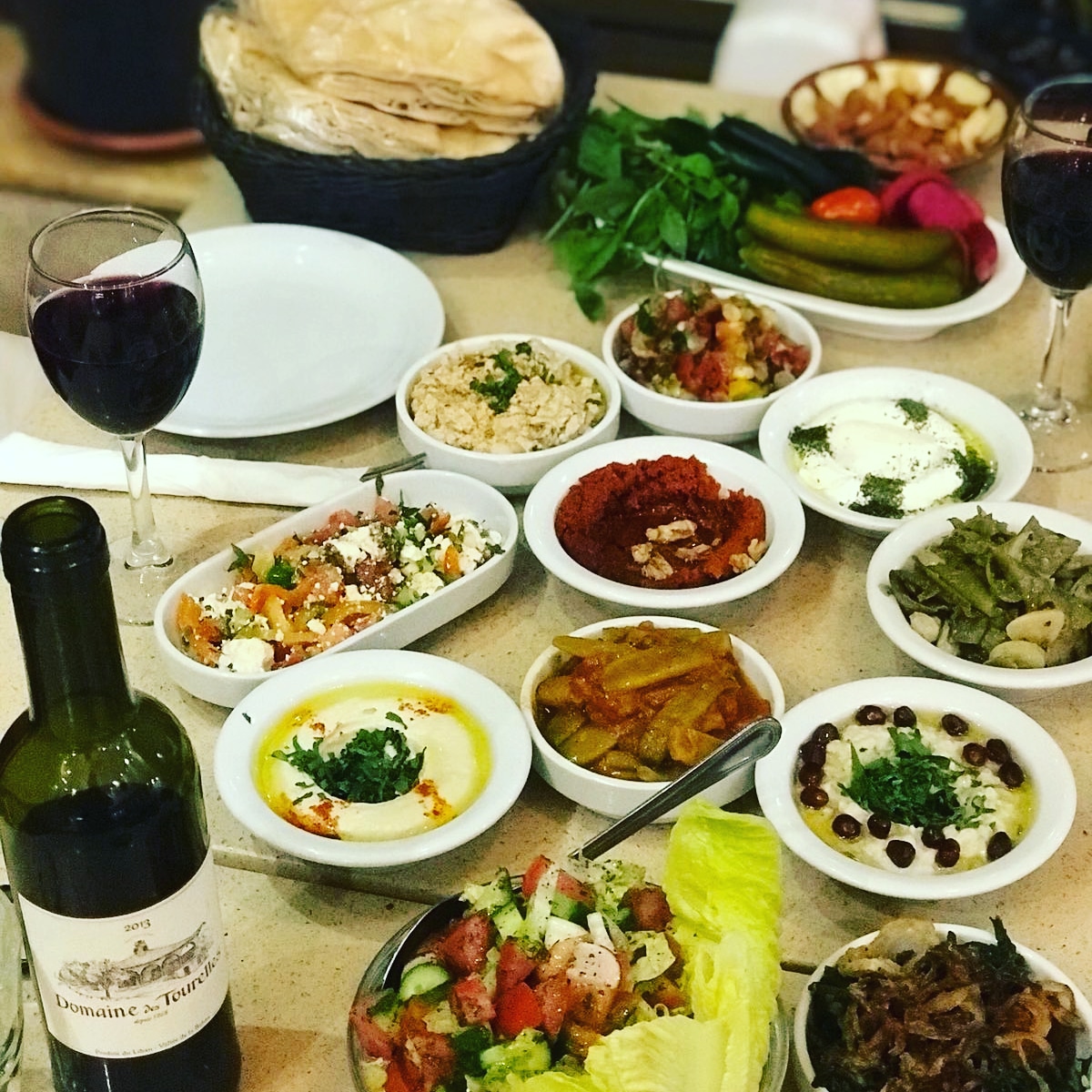 A full mezze spread of small plates with a bottle of wine