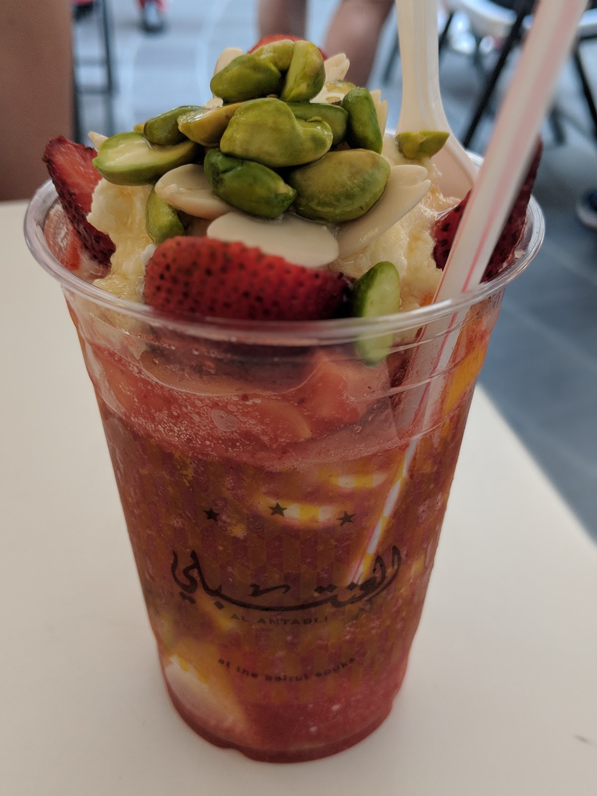 Strawberry fruit cocktail topped with pistachio in a logo cup