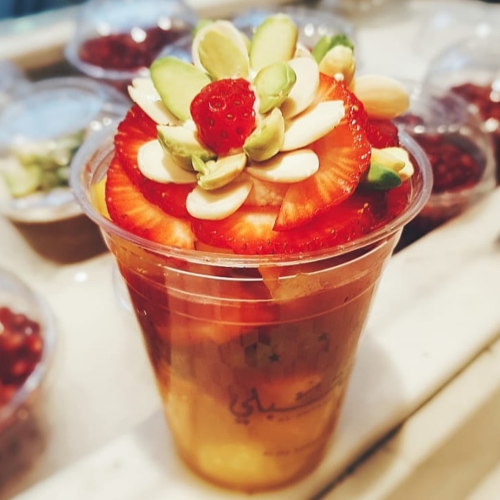 A cocktail cup with strawberries, almonds and pistachio on the rim
