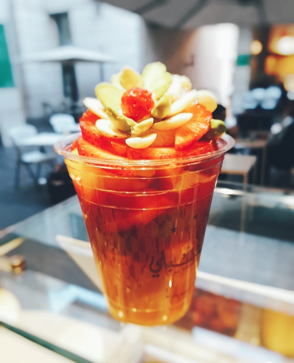 A jallab cup with pine nuts and raisins on the table