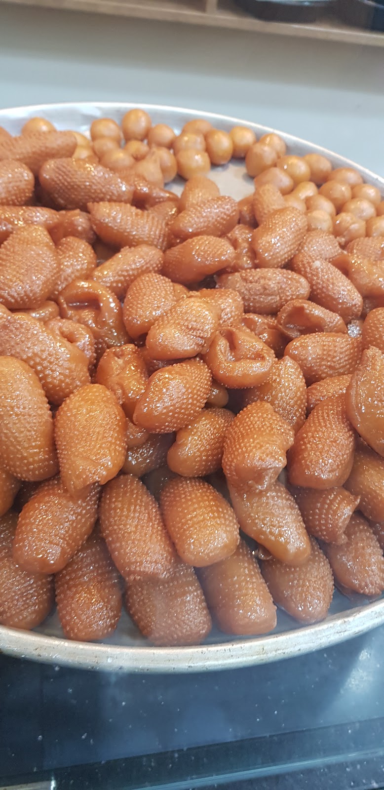 A pile of golden syrup-dipped sweets on a metal tray