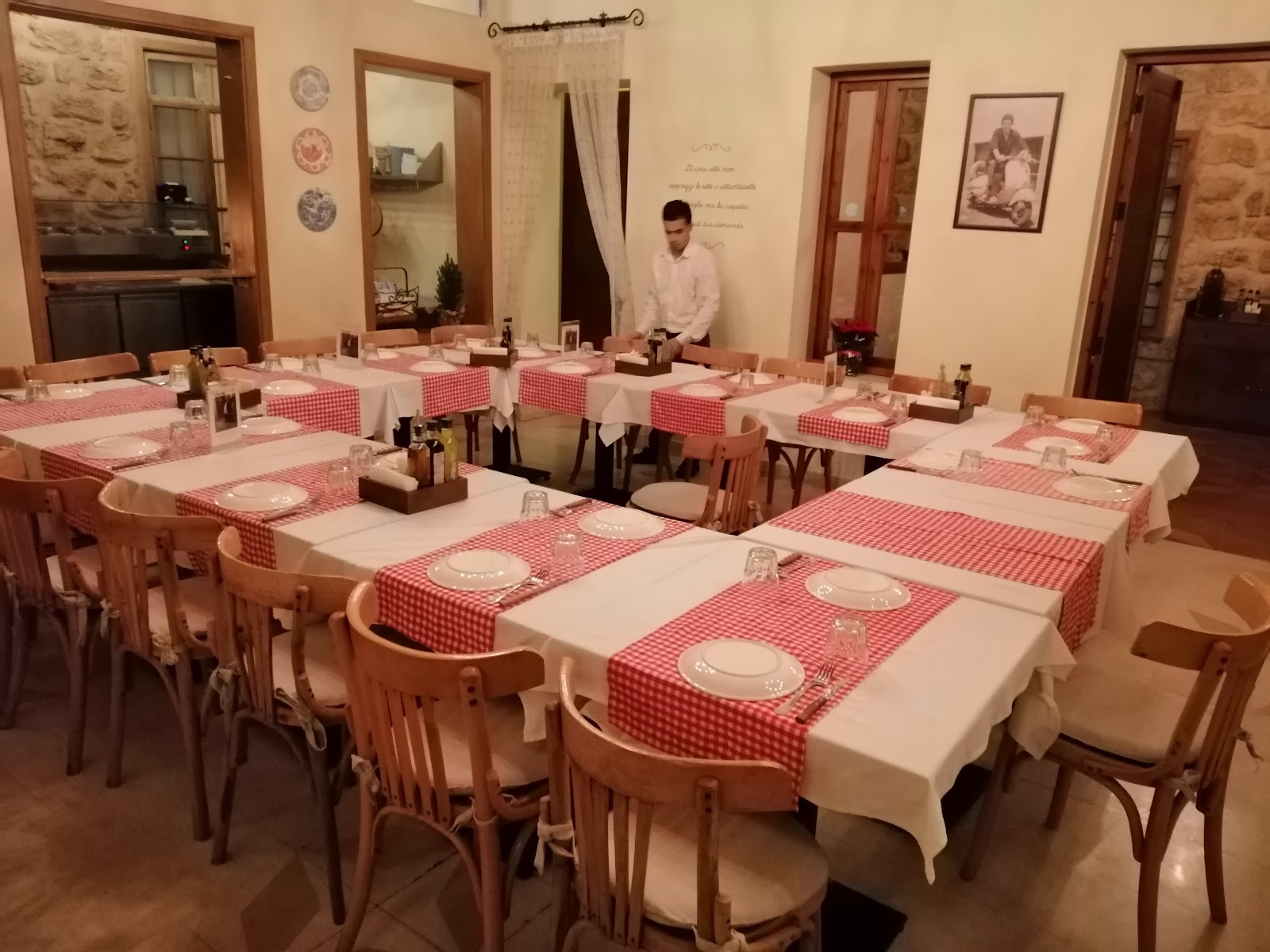 The trattoria room set for service, checked runners on every table