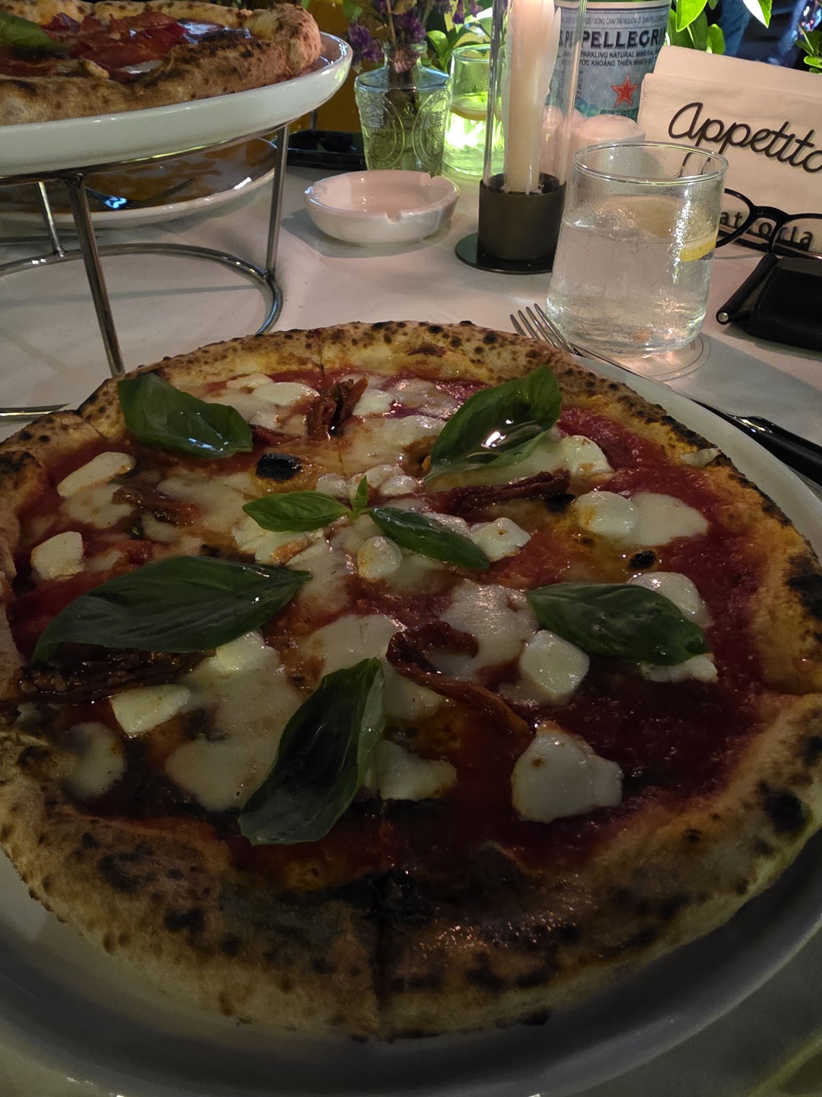 A margherita pizza at the table by the window