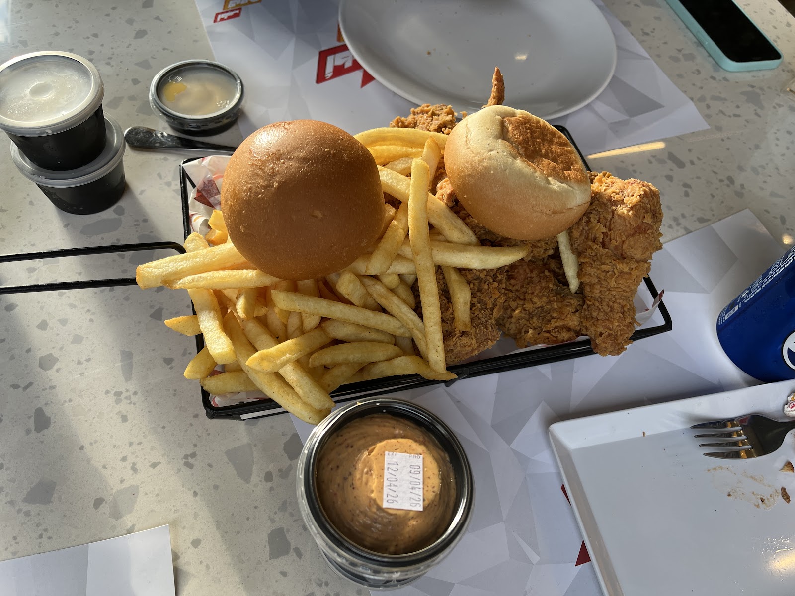 A serving rack with burger, crispy chicken and fries on the terrazzo table