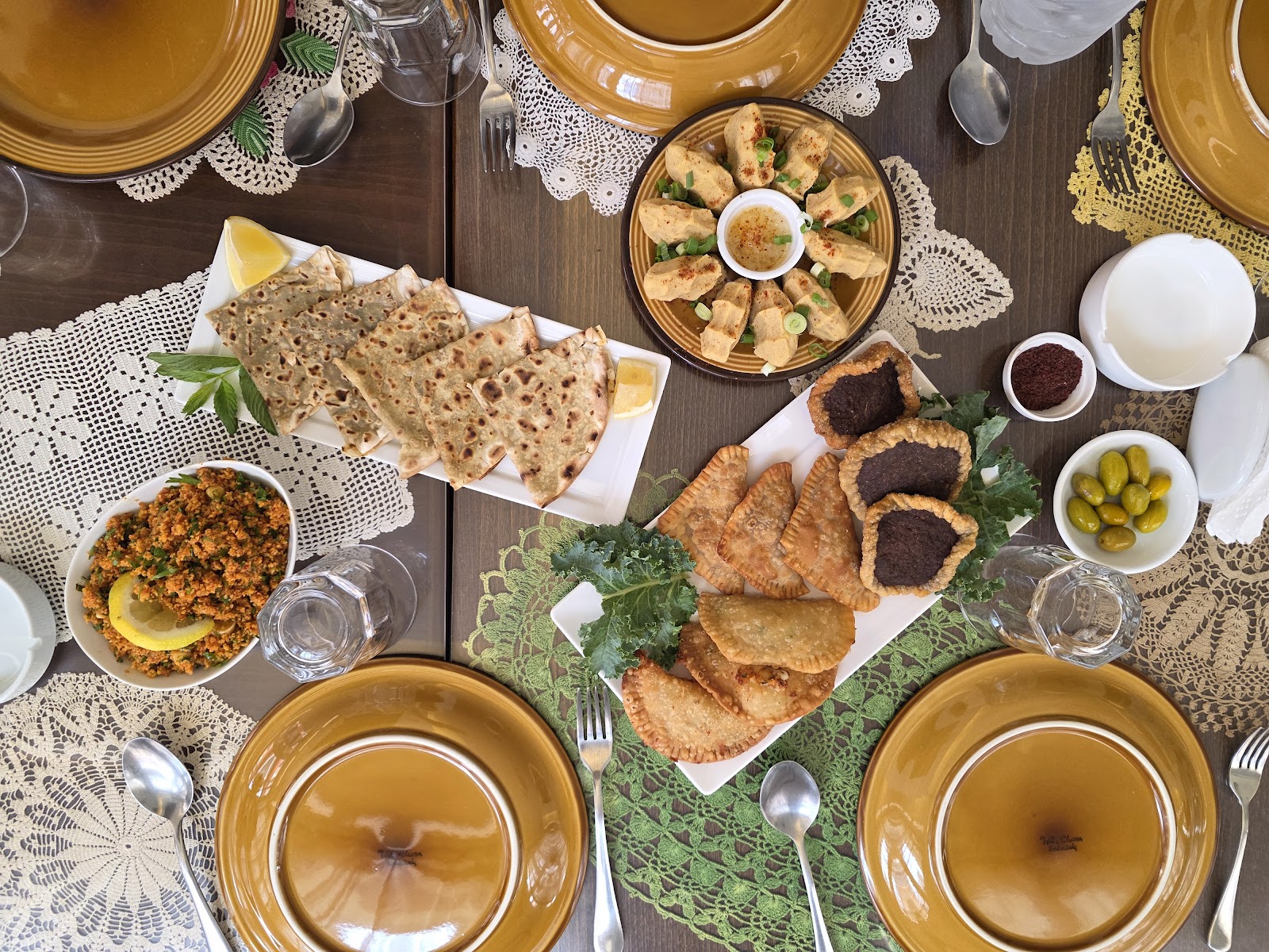 A full Armenian table from above: kibbeh, pastries, dips and salads on lace cloth