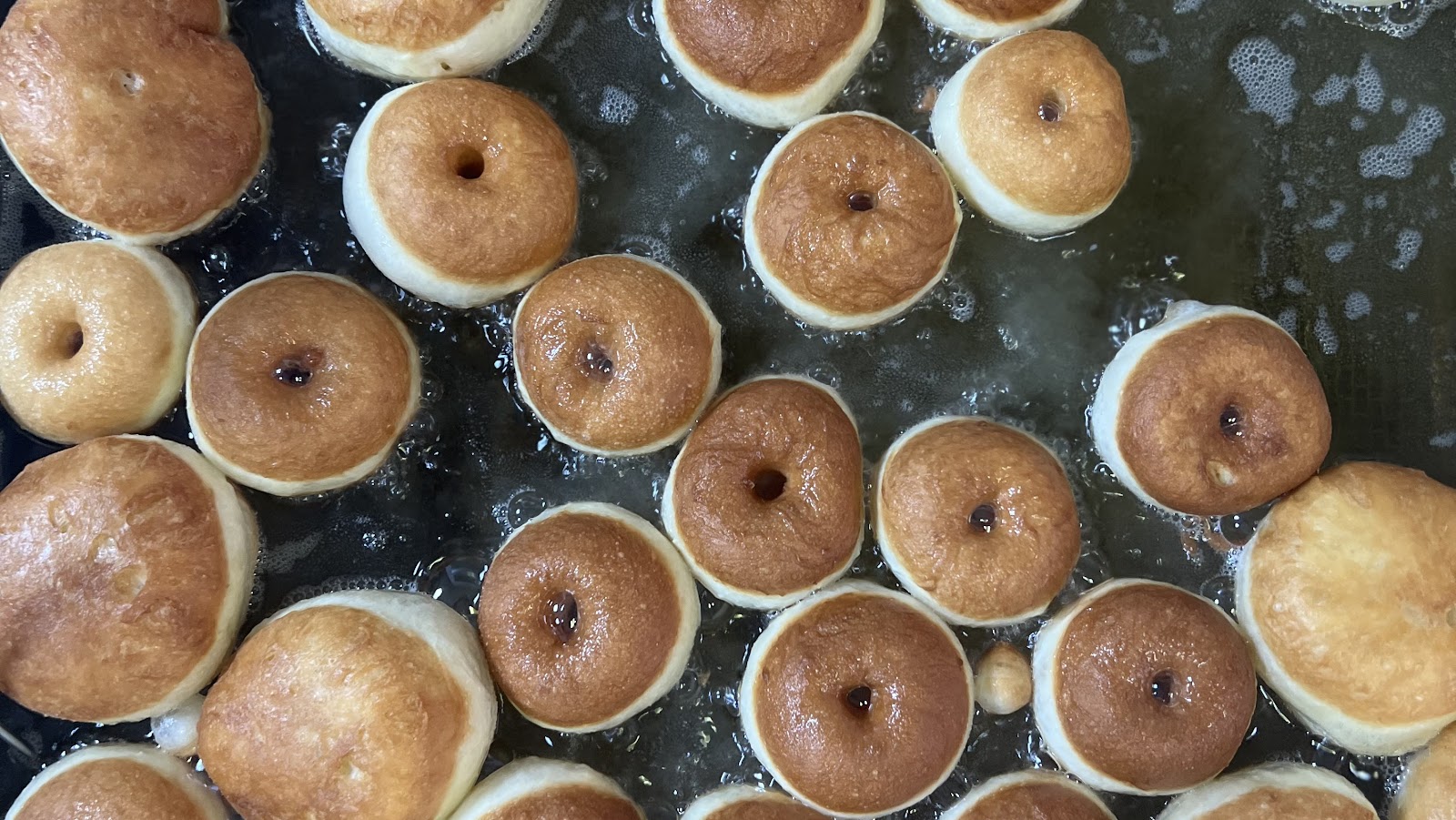 A tray of glazed brioche rings straight out of the fryer