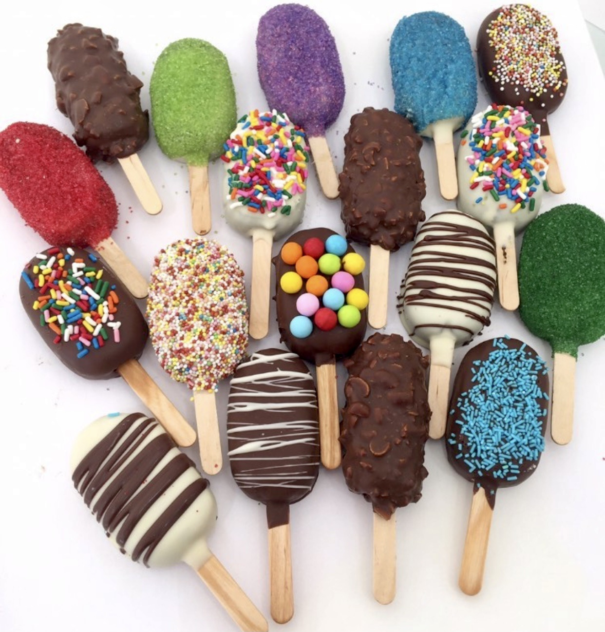 Chocolate-dipped cakesicles on sticks in many colours
