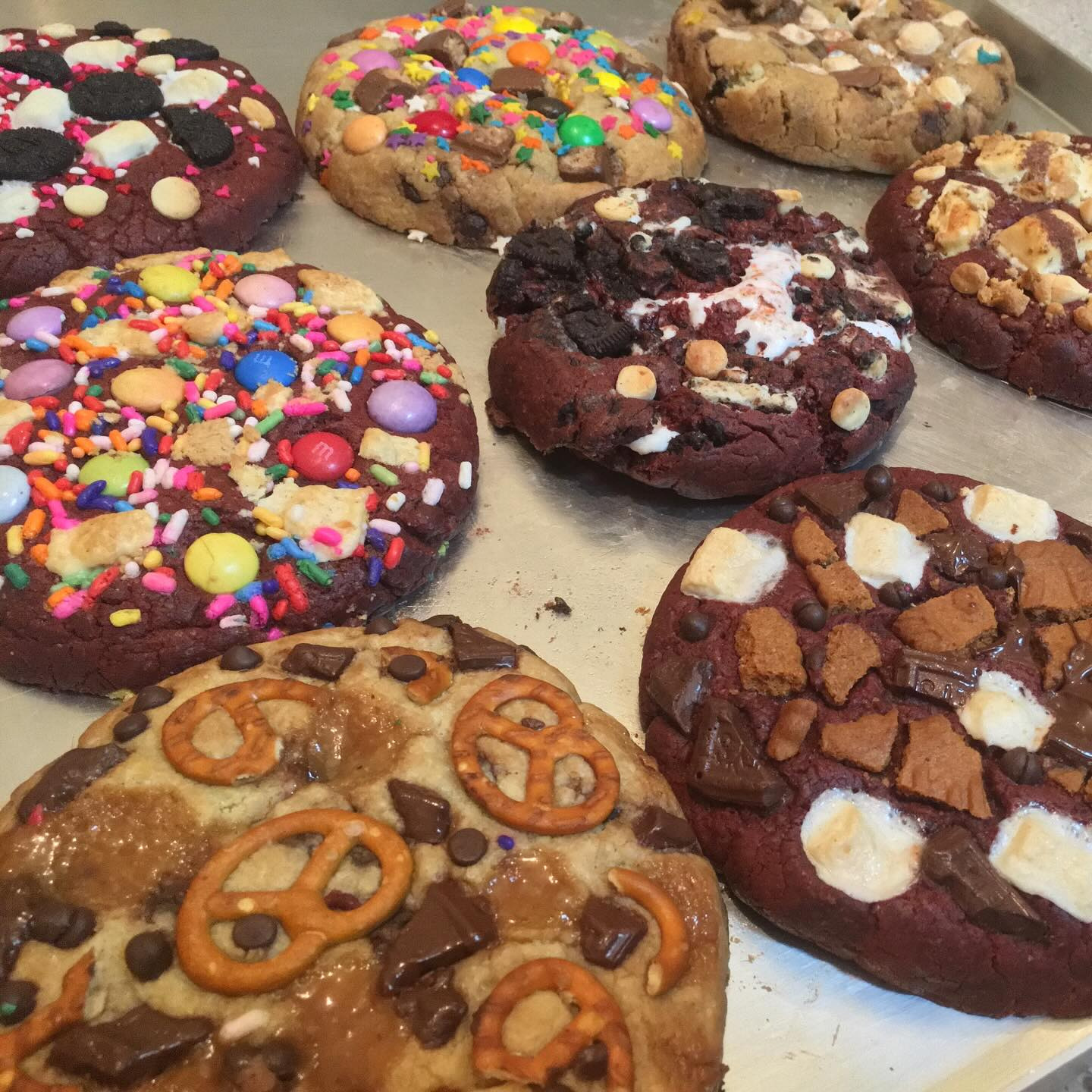 A tray of stuffed cookies topped with pretzels, marshmallow and chocolate