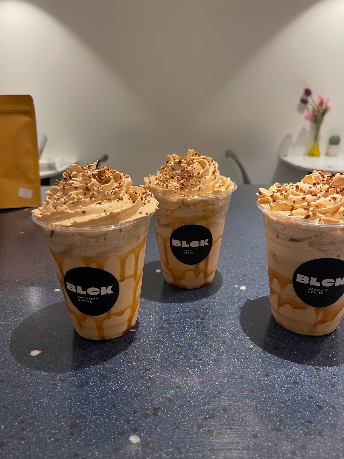 Three iced caramel drinks with cream on the terrazzo table