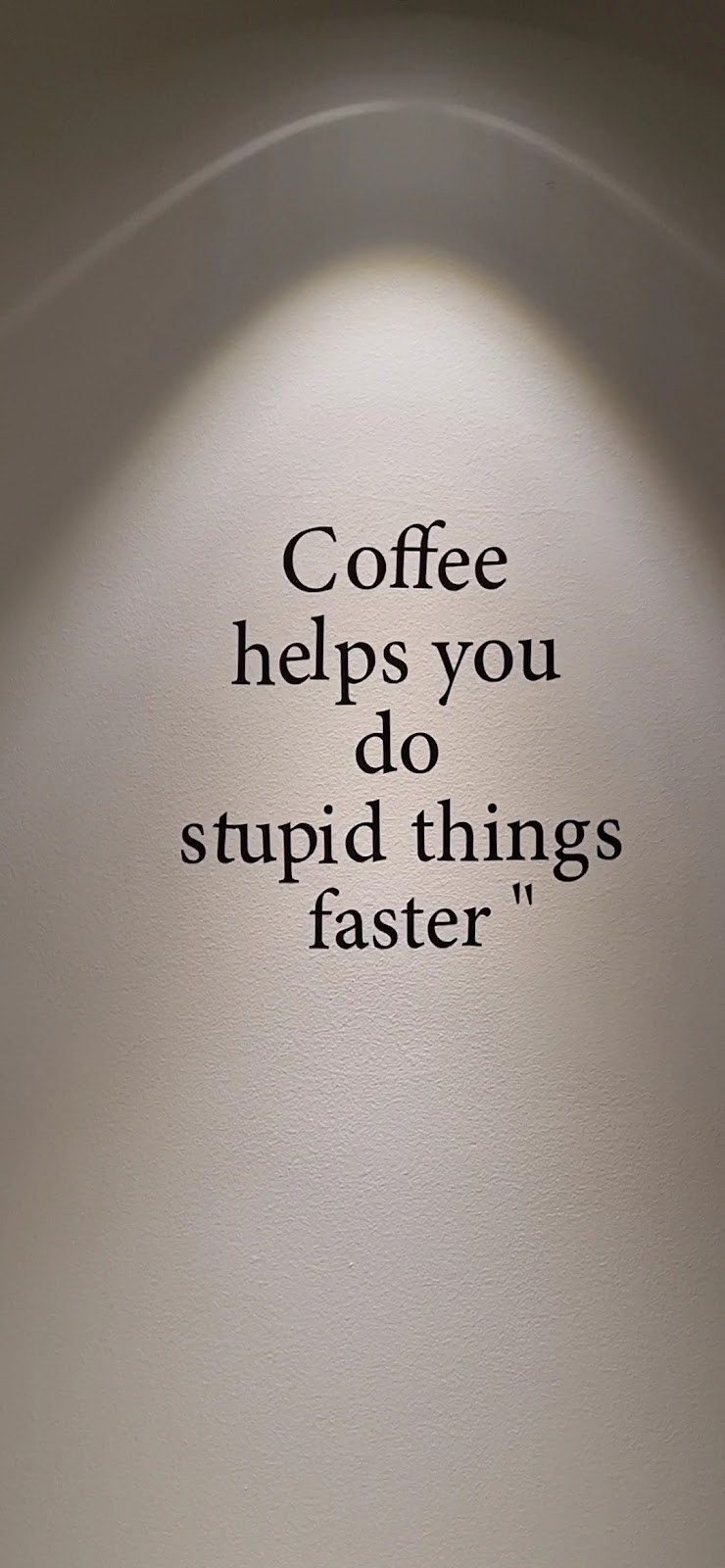 The painted wall inside BLCK reading Coffee helps you do stupid things faster