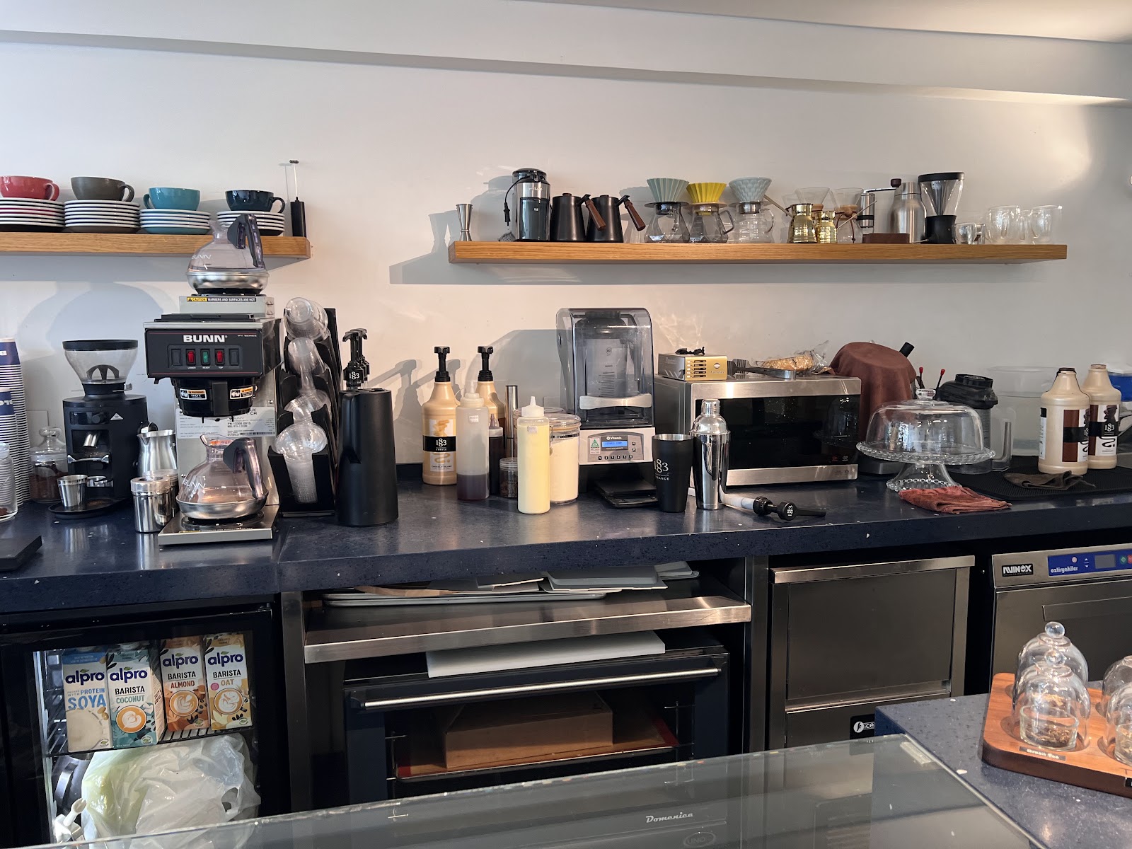 The espresso machines and grinders on the black back bar