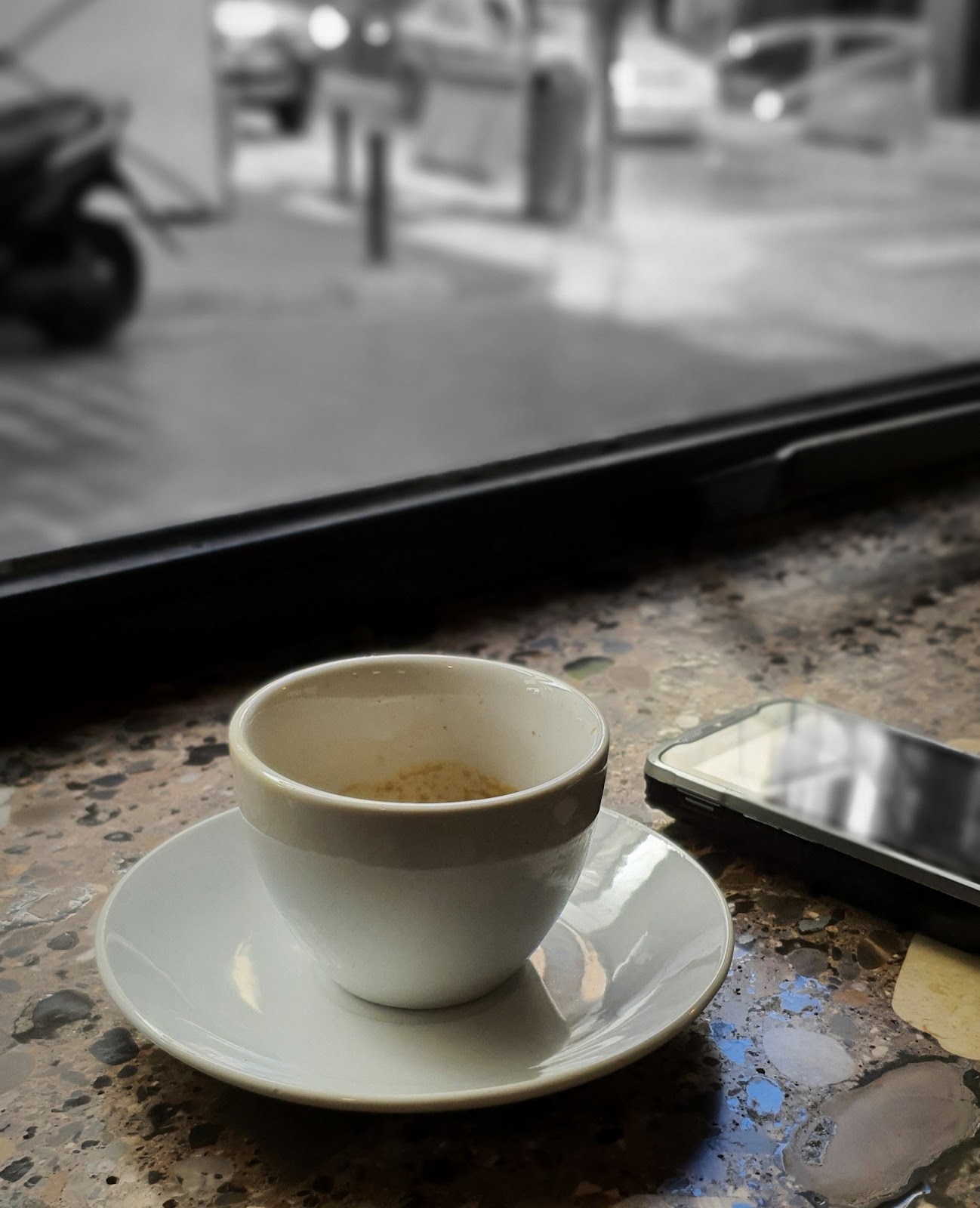 An espresso cup and phone on the counter at night