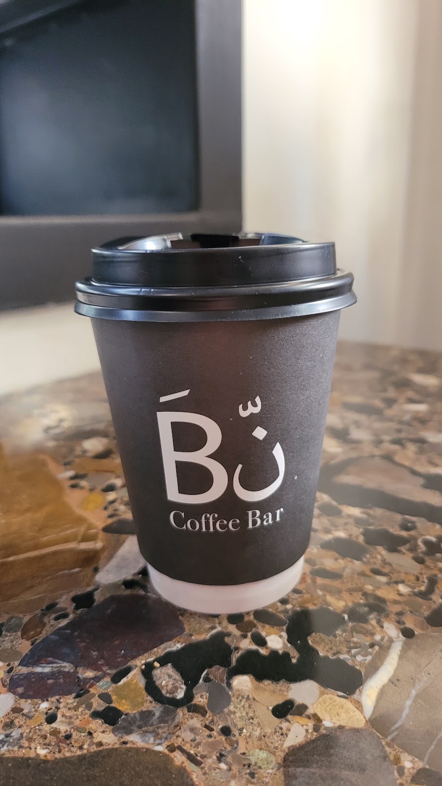 A Bn branded paper cup on the terrazzo counter