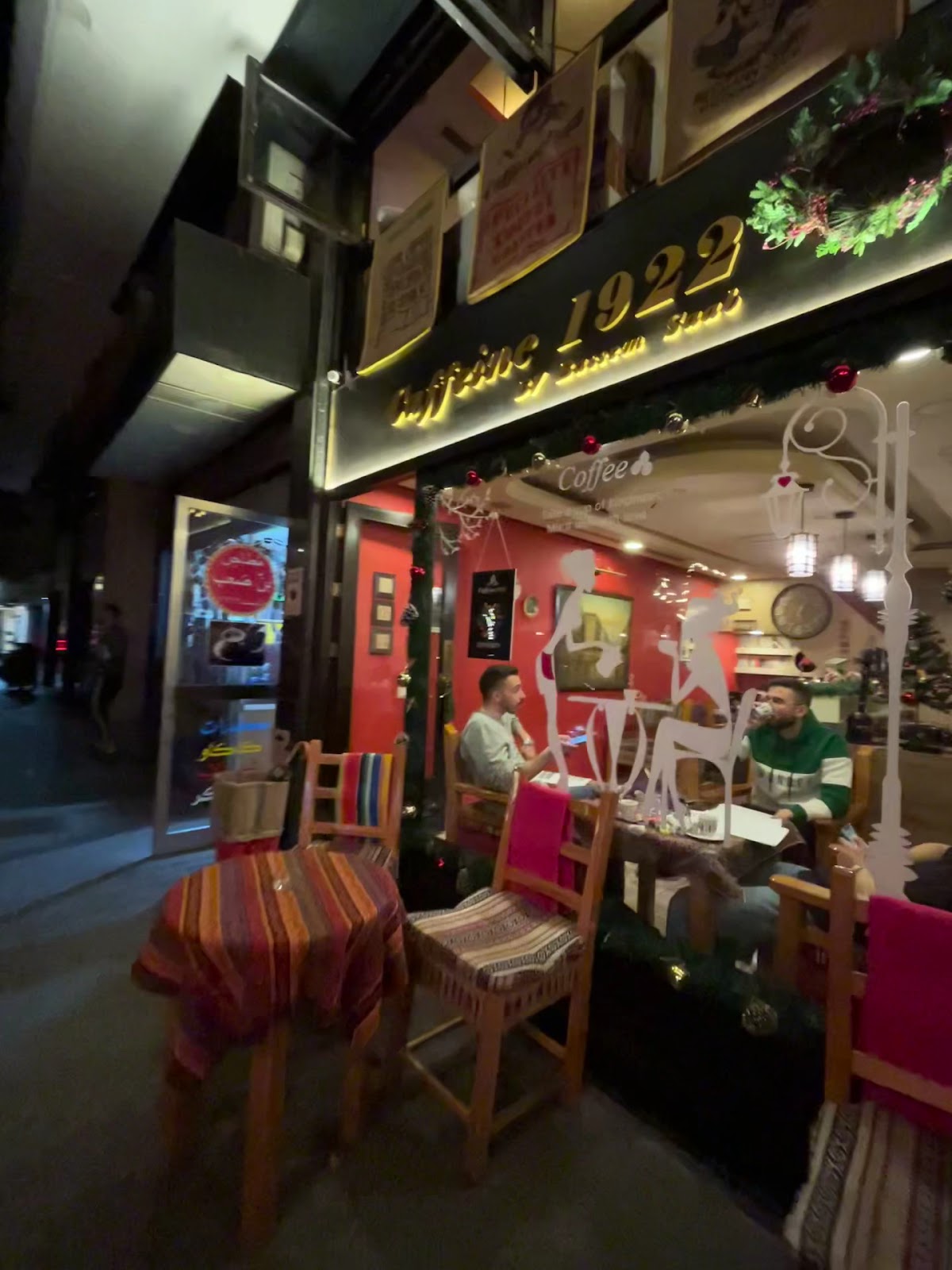 The shop at night, gold lettering glowing over the red frontage