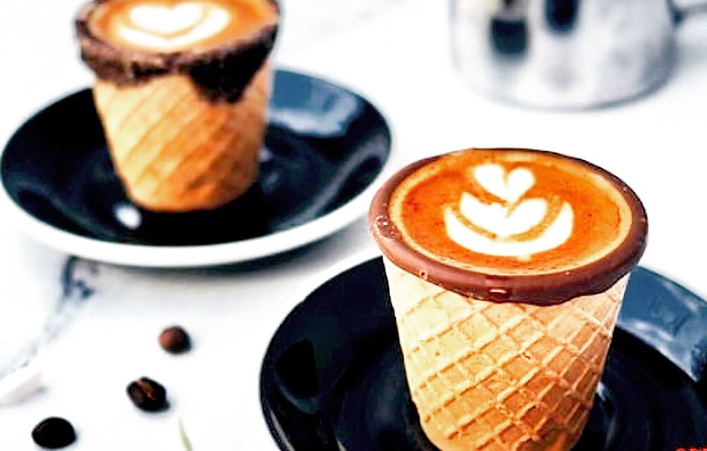 Latte art served inside a chocolate-rimmed waffle cone