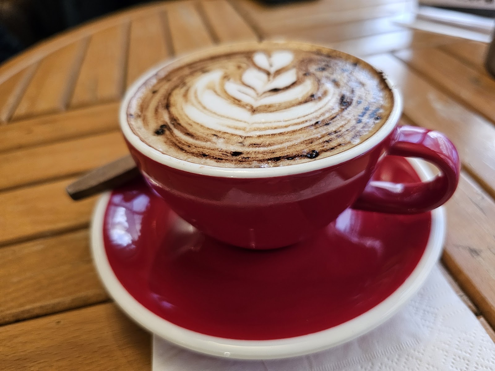 A cappuccino dusted with chocolate in a red cup