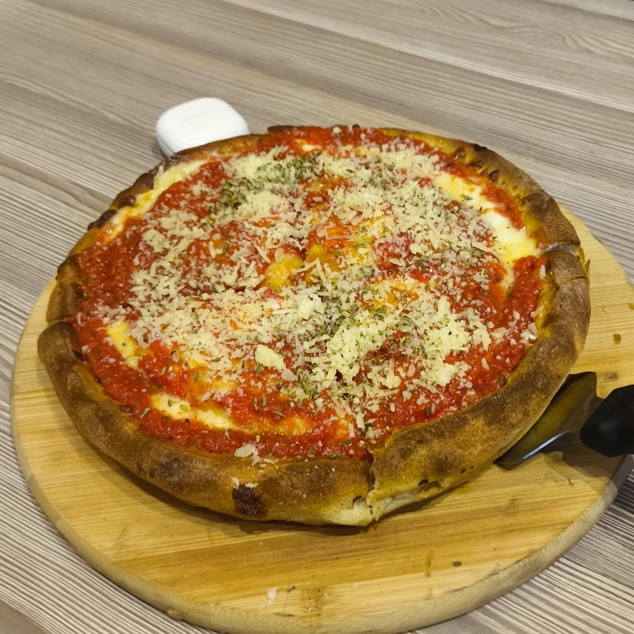A whole Chicago Pizza deep dish on its wooden board, shot from above