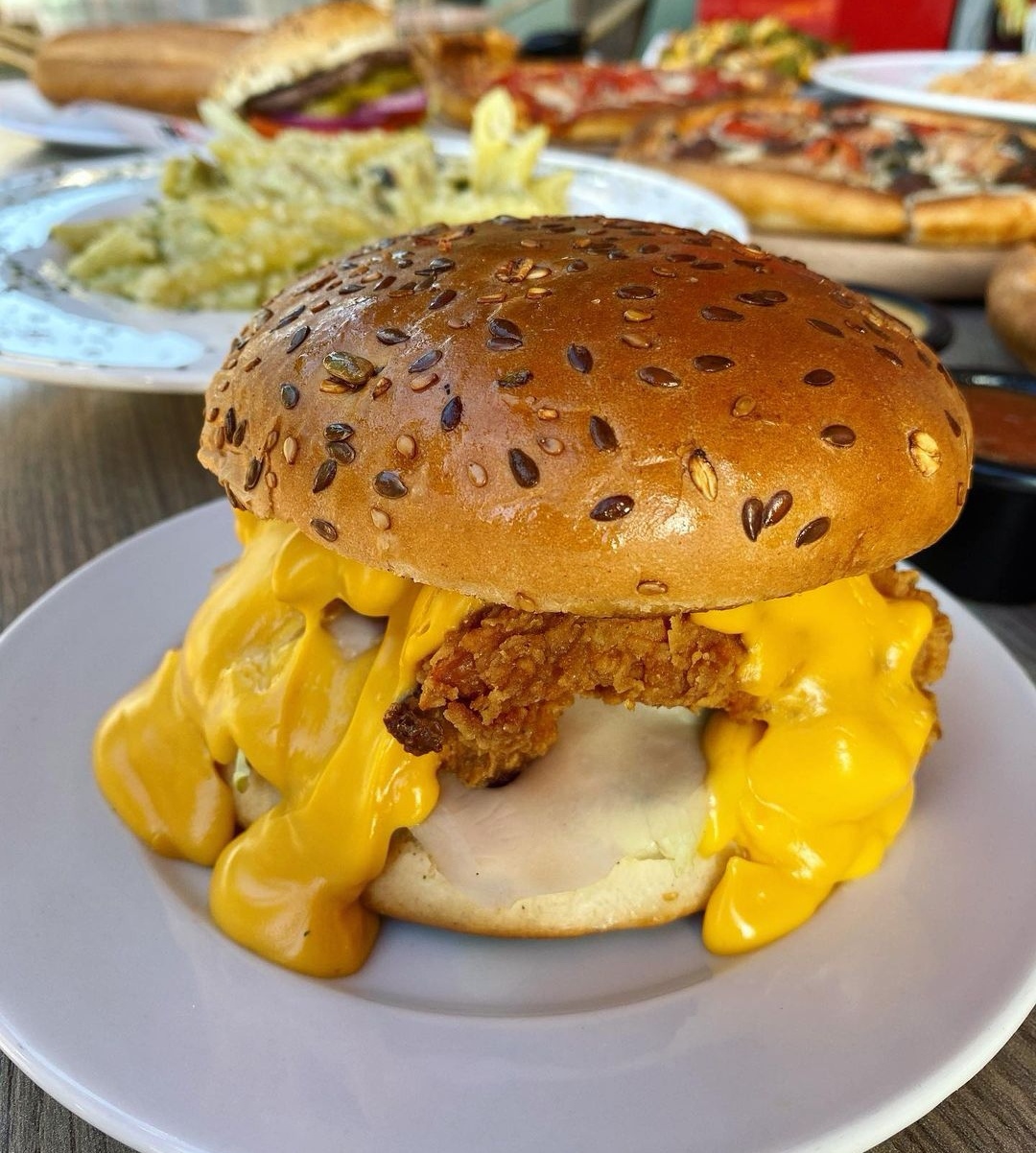 A crispy chicken burger dripping with cheese sauce