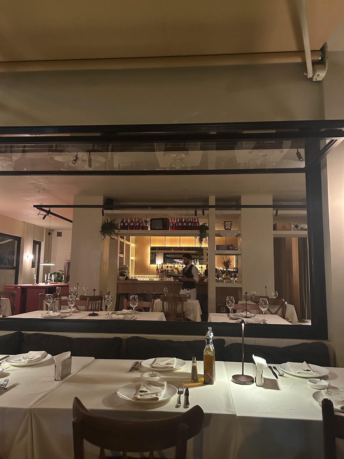 The dining room at night, white tablecloths and the lit bar
