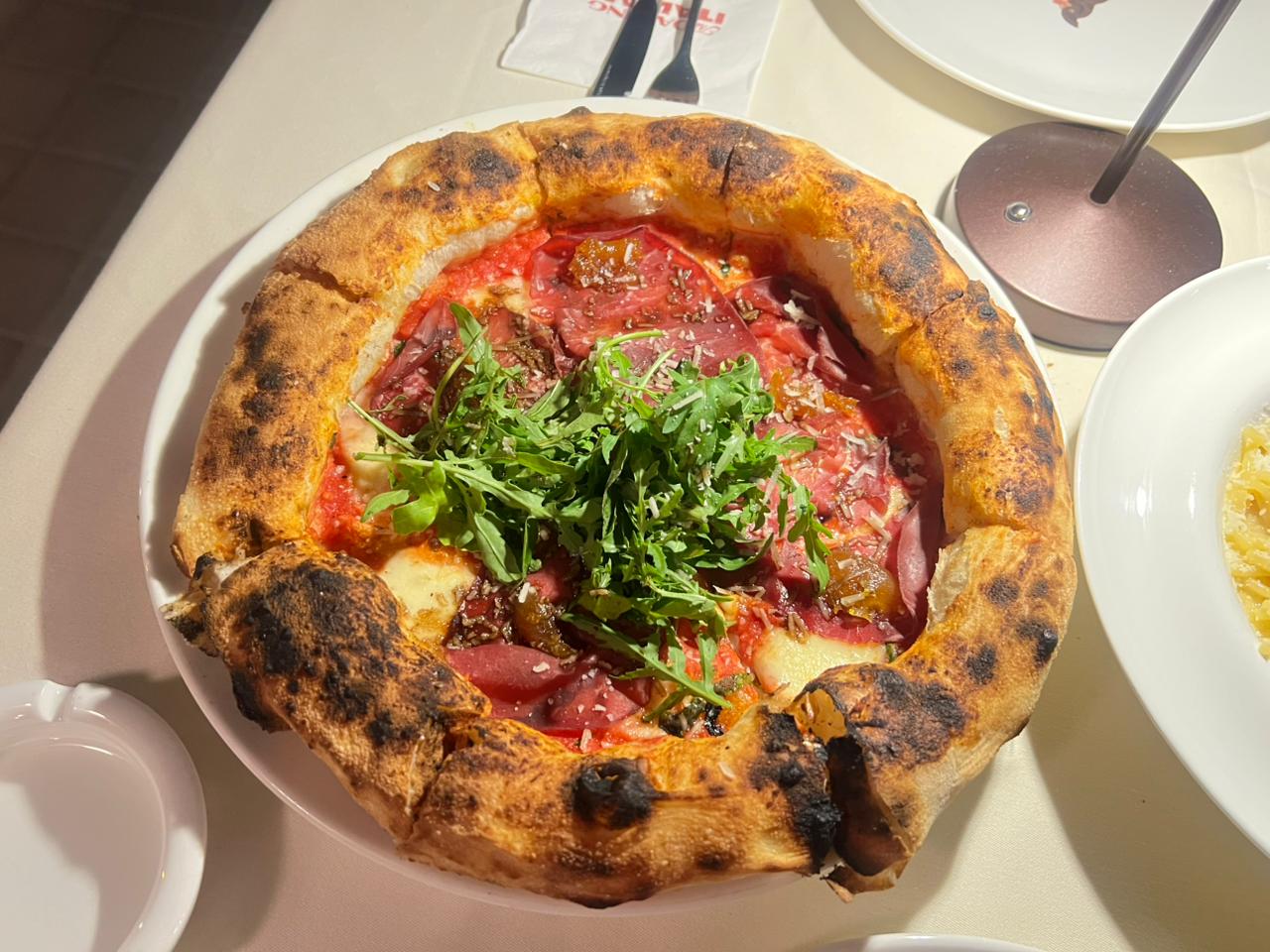 A whole Daring Italian pizza photographed from directly above on a white plate