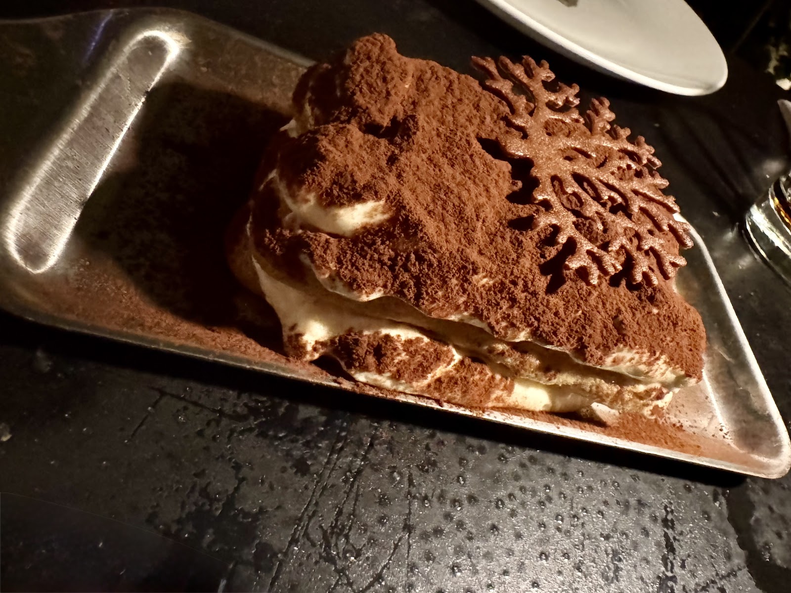 A tiramisu slab dusted with a cocoa stencil pattern