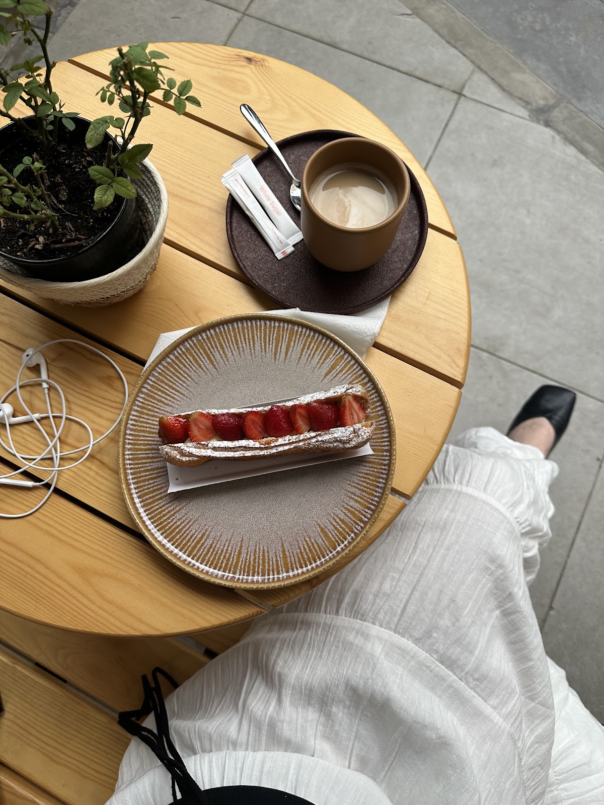 An eclair and a coffee on the marble table by the window