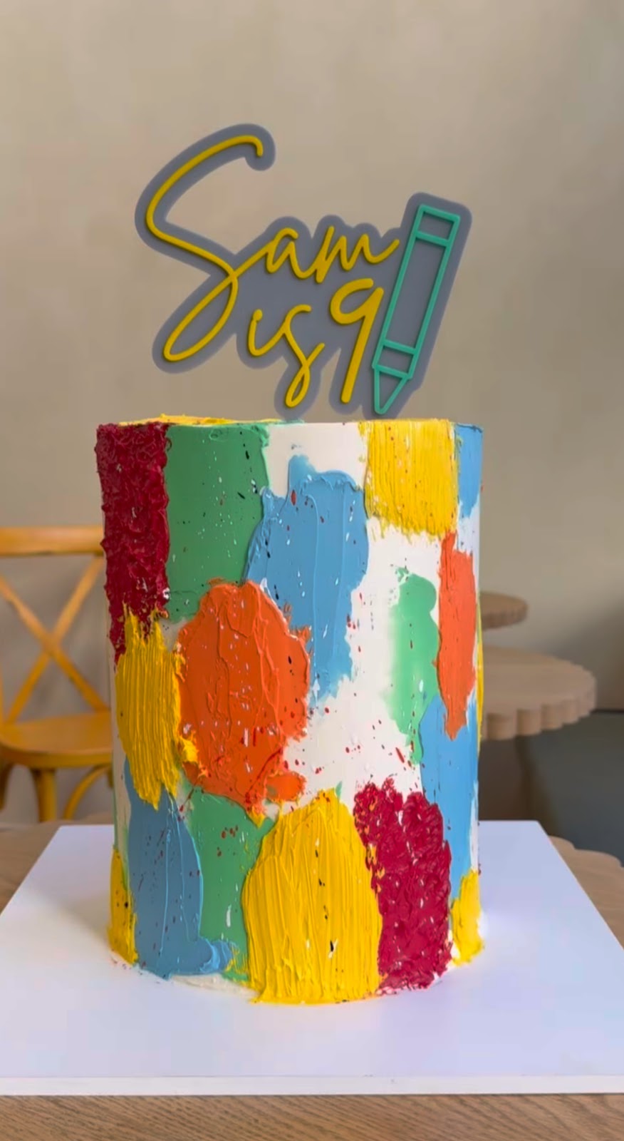 A colorful hand-painted birthday cake with a Sam is 9 topper