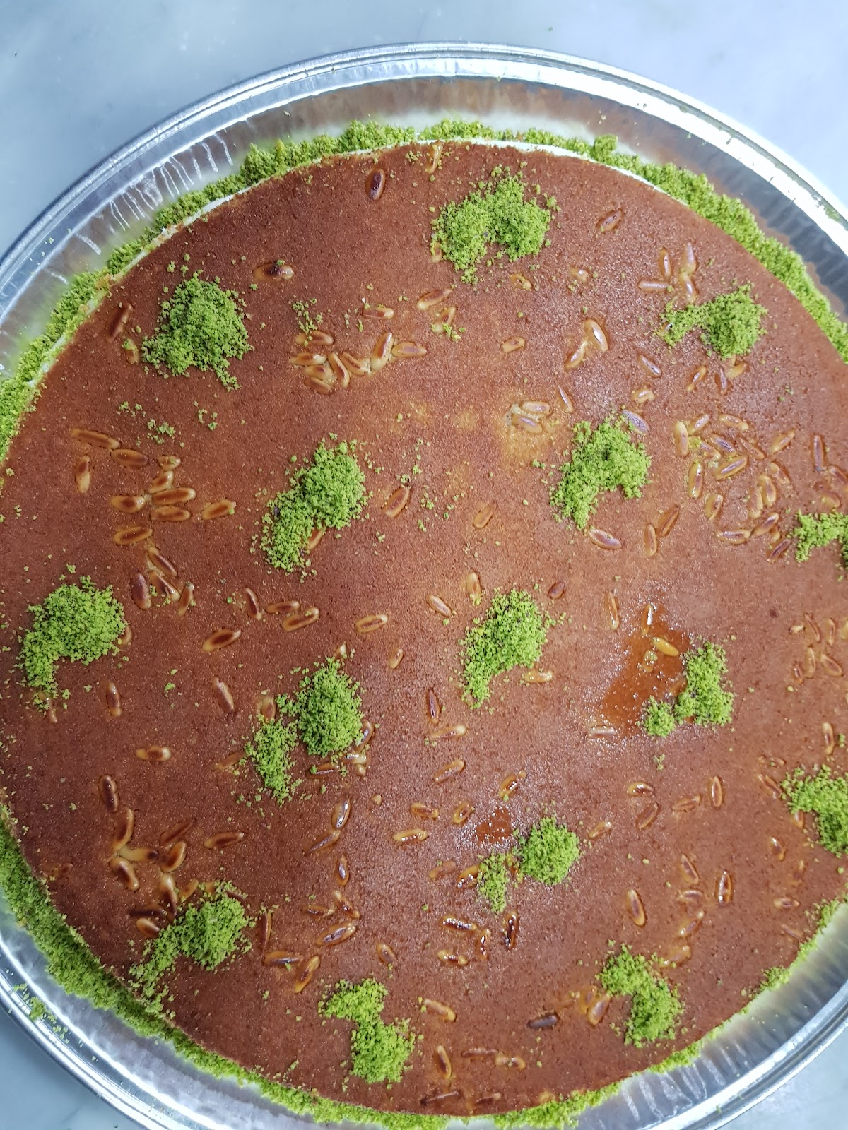 A full round knafeh tray with pistachio, seen from above