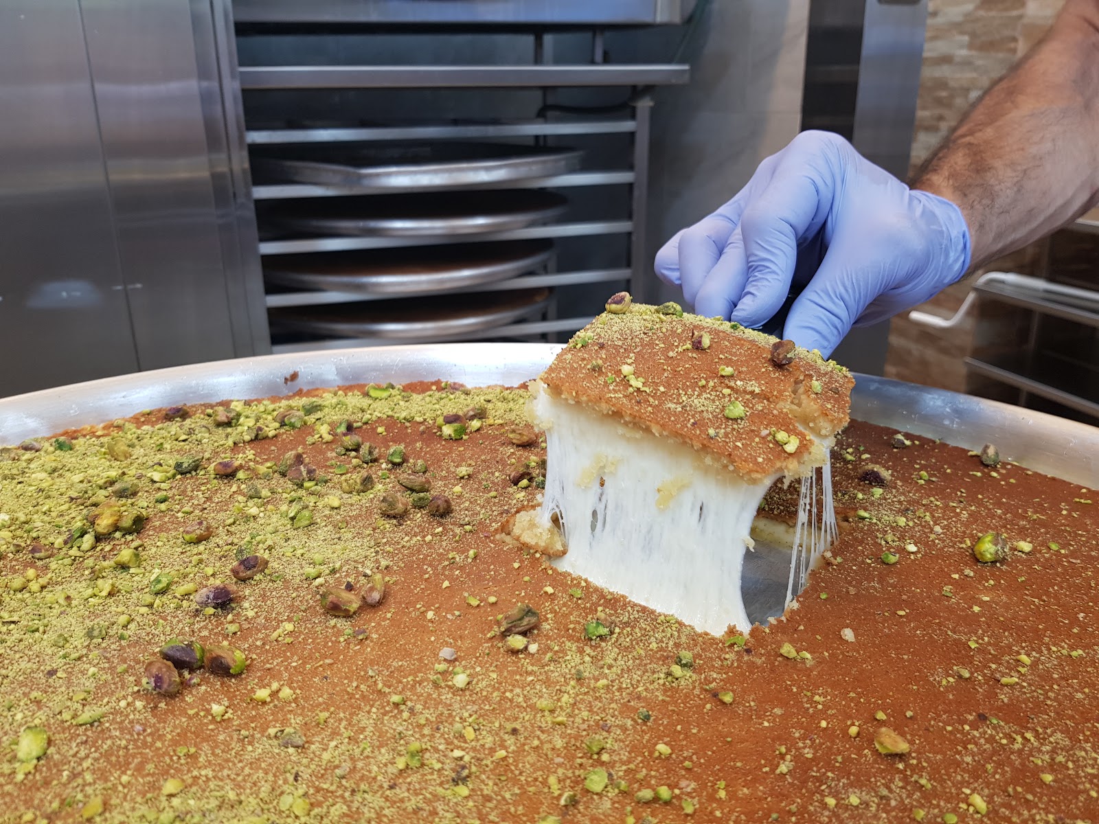 A square of knafeh lifted off the tray at Haitham Knafeh King, the cheese stretching