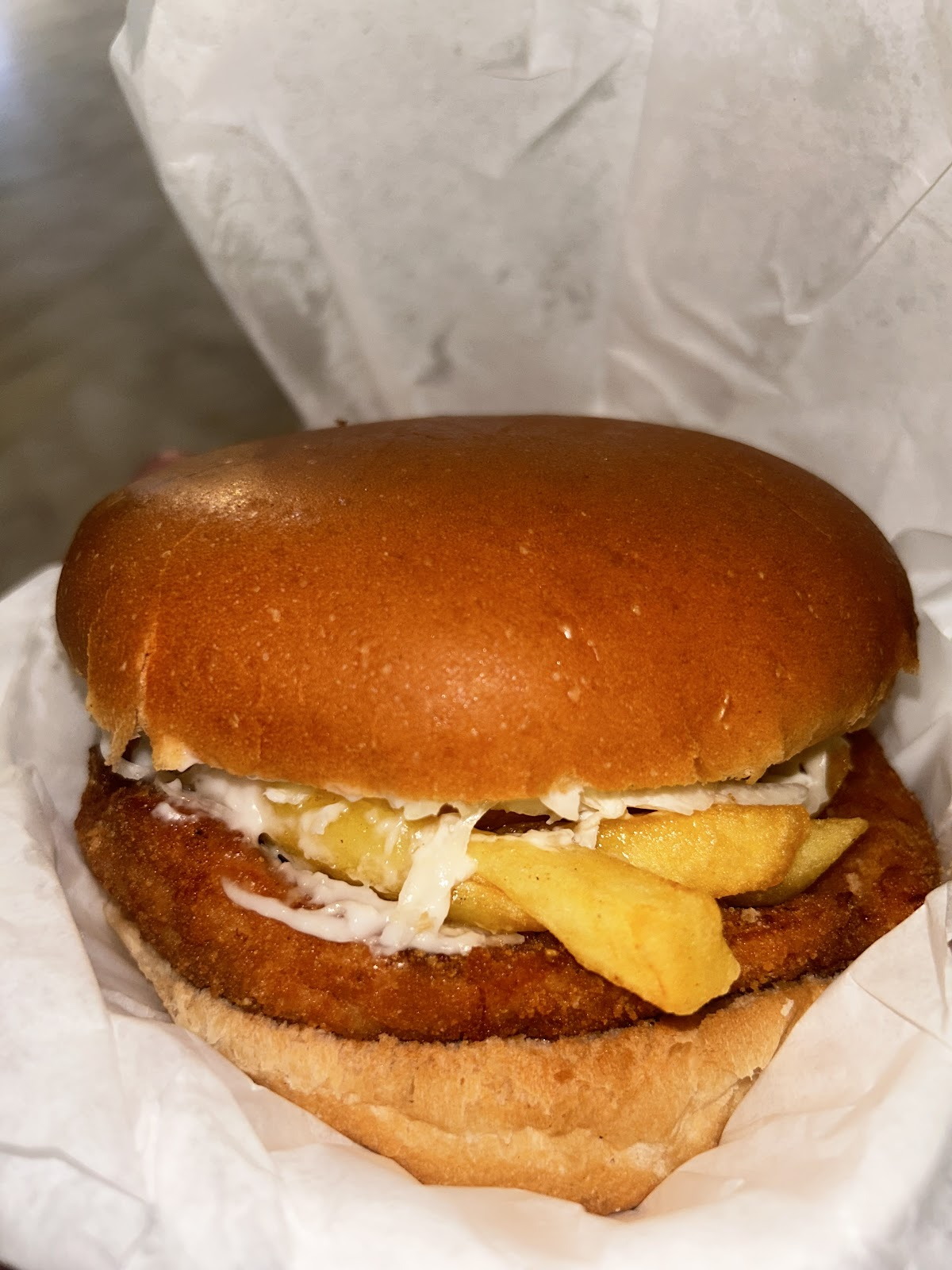 The escalope burger close up, chicken, fries and coleslaw inside the bun