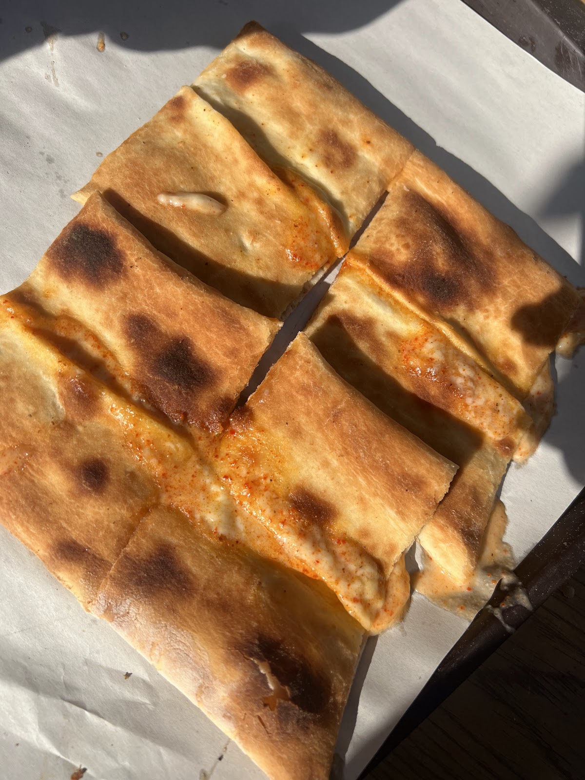 Crisp-edged boereg sticks cut on baking paper in the sun