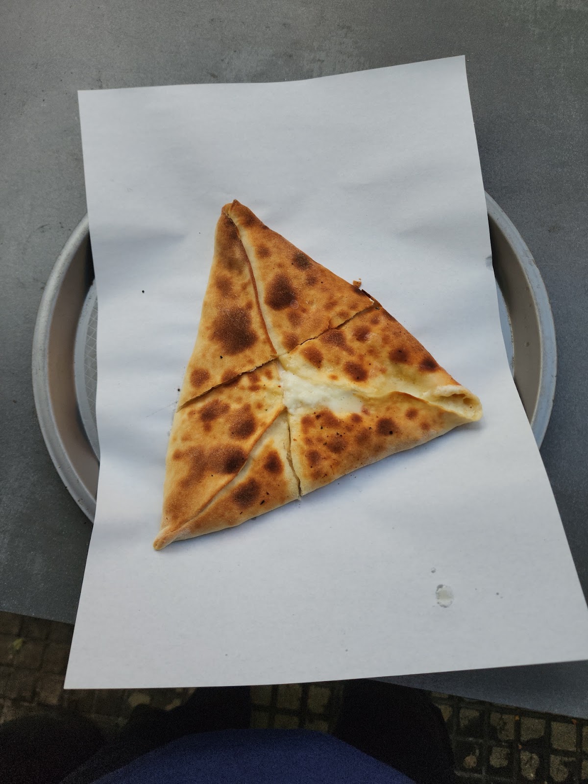A triangle cheese boereg served on paper on a plate
