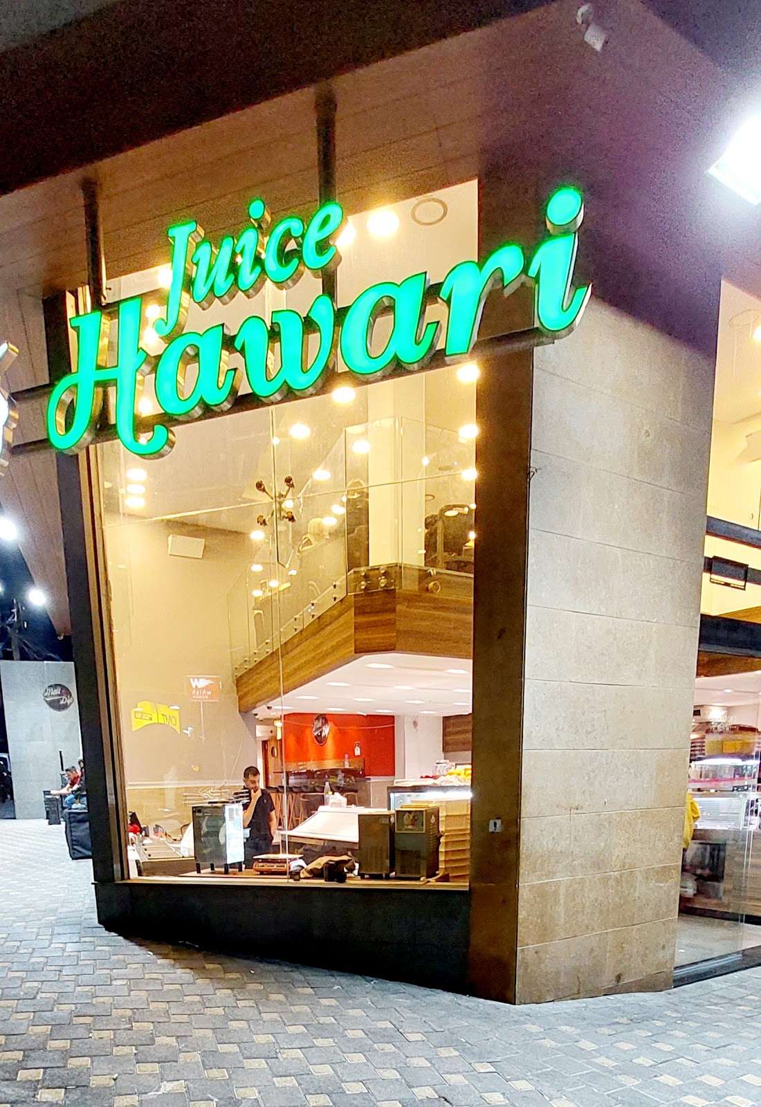The Juice Hawari corner shop glowing green at night