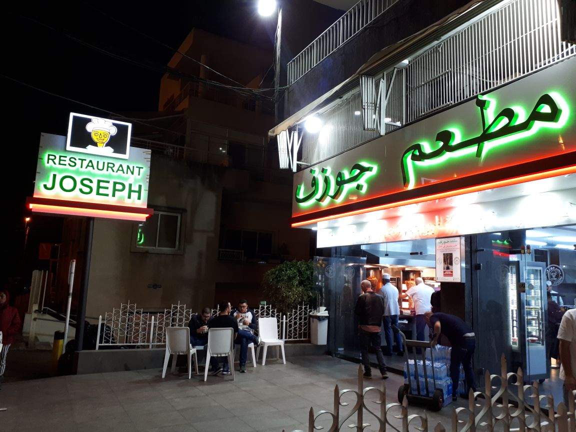The Restaurant Joseph corner at night, both neon signs lit