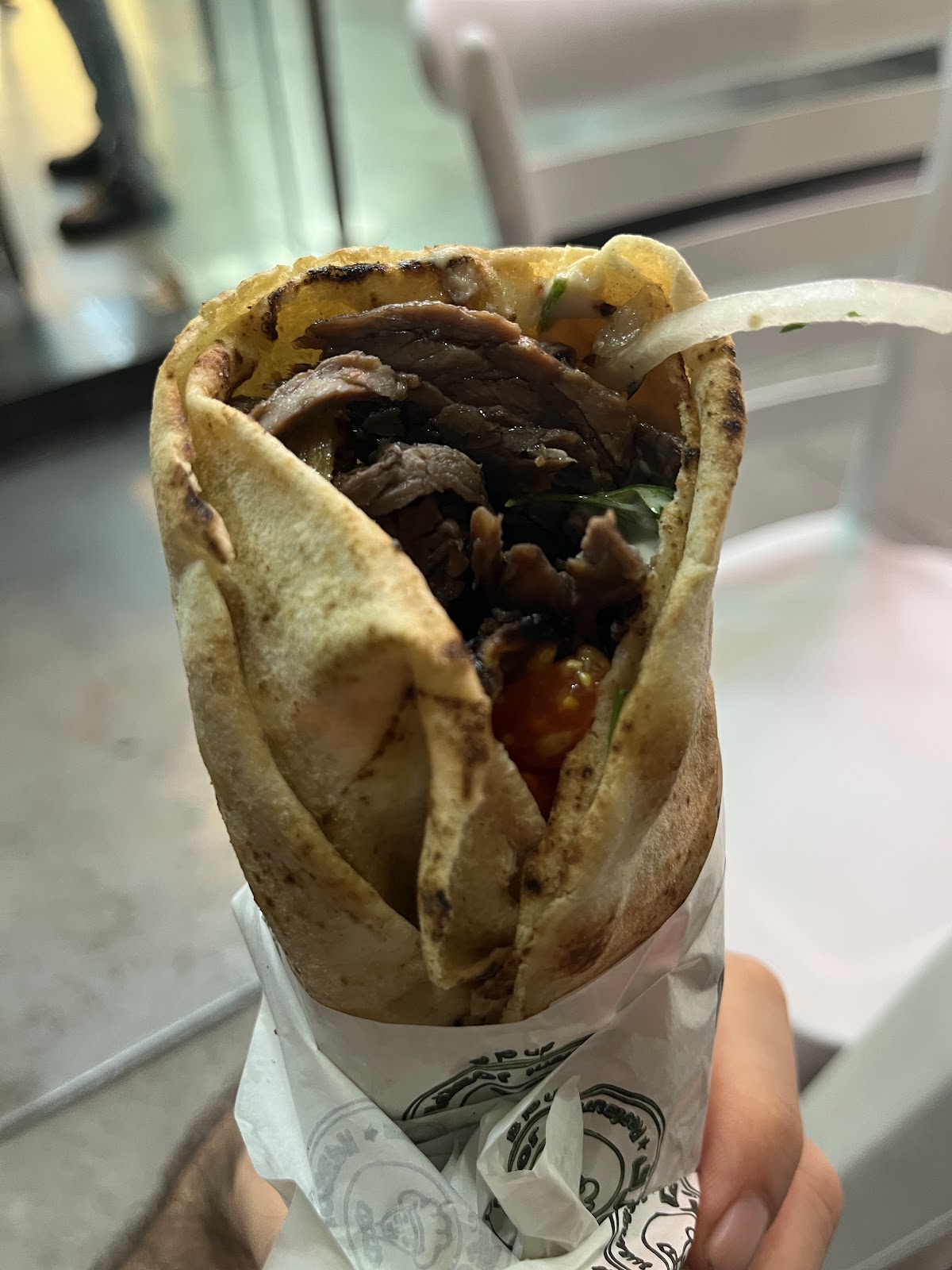 A wrapped shawarma sandwich in its printed paper