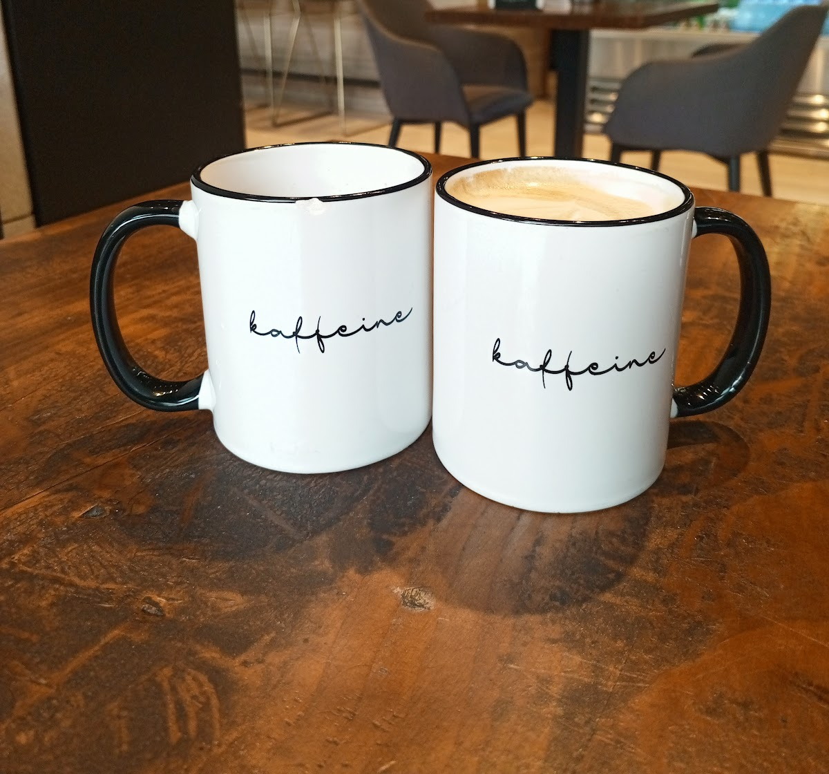 Two white Kaffeine mugs side by side on the wooden table