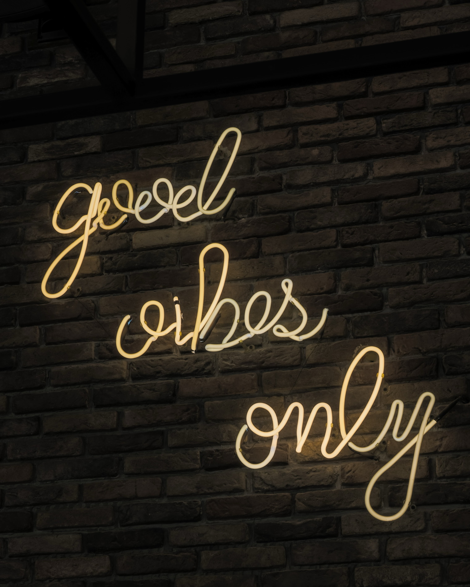 The good vibes only neon script glowing on the black brick wall