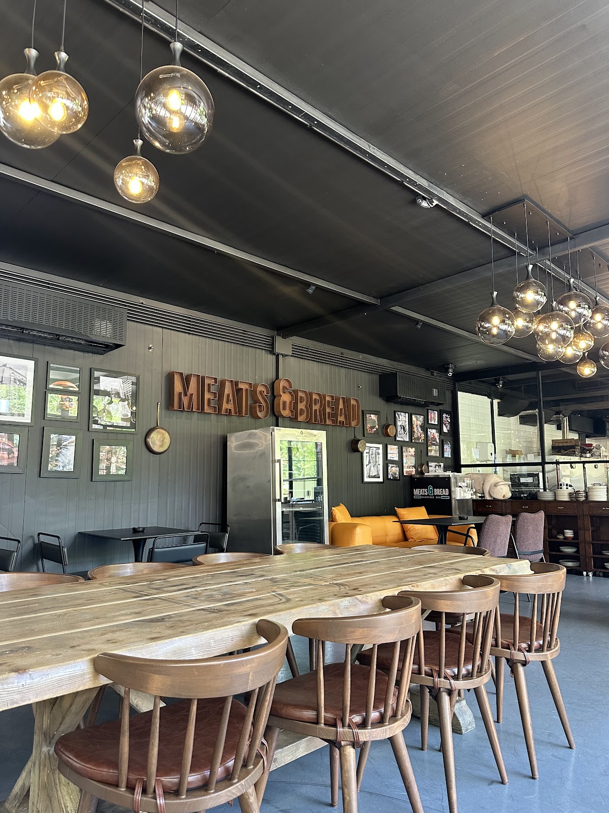 The wood tables and hanging bulbs inside Meats and Bread