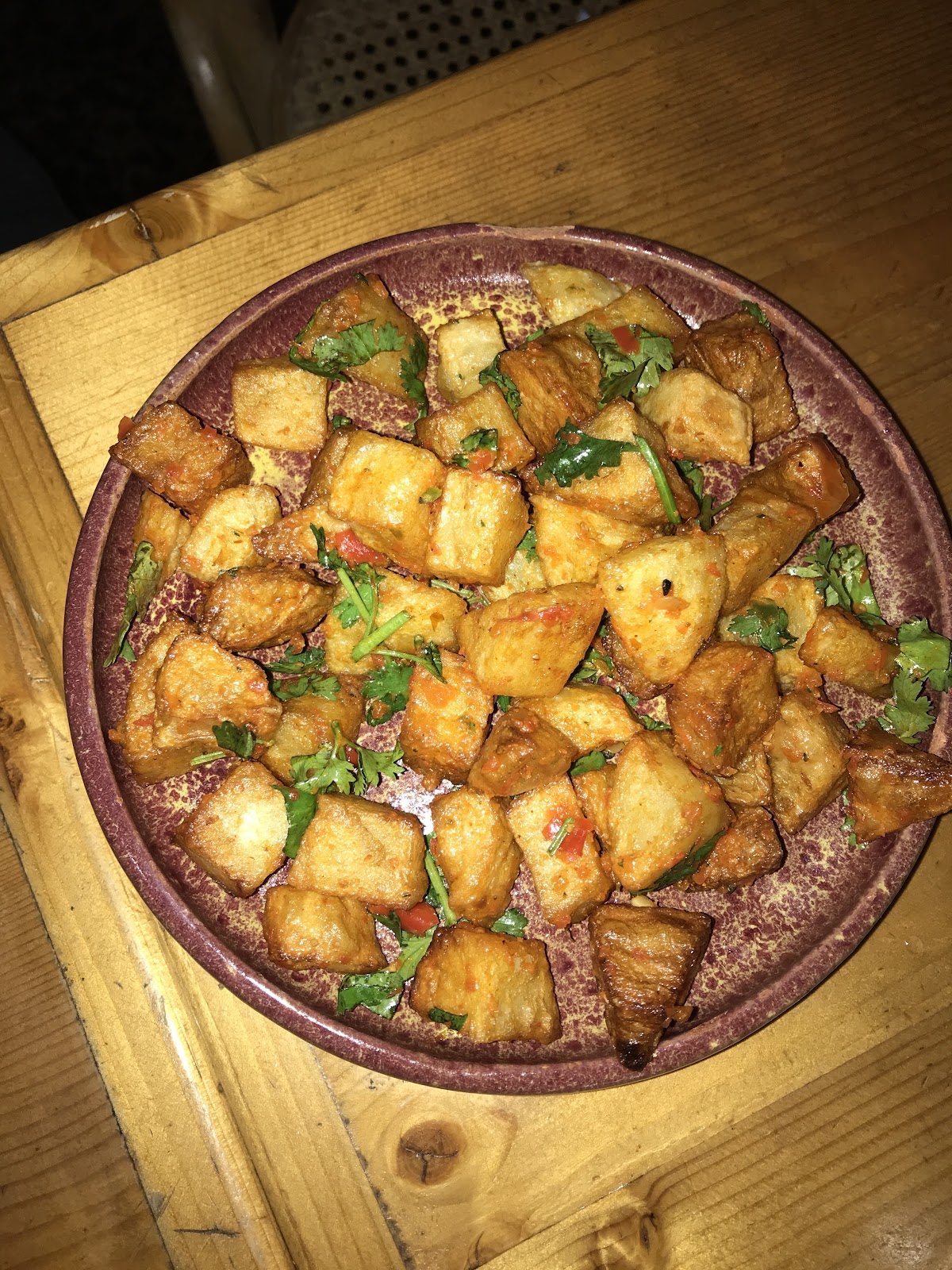 Batata harra served in a clay dish on the wooden table