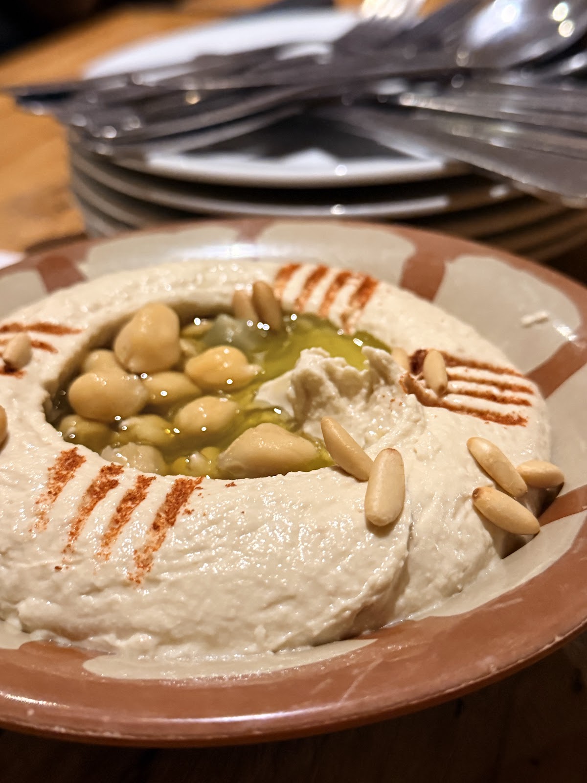 Hummus finished with pine nuts and olive oil in a patterned bowl