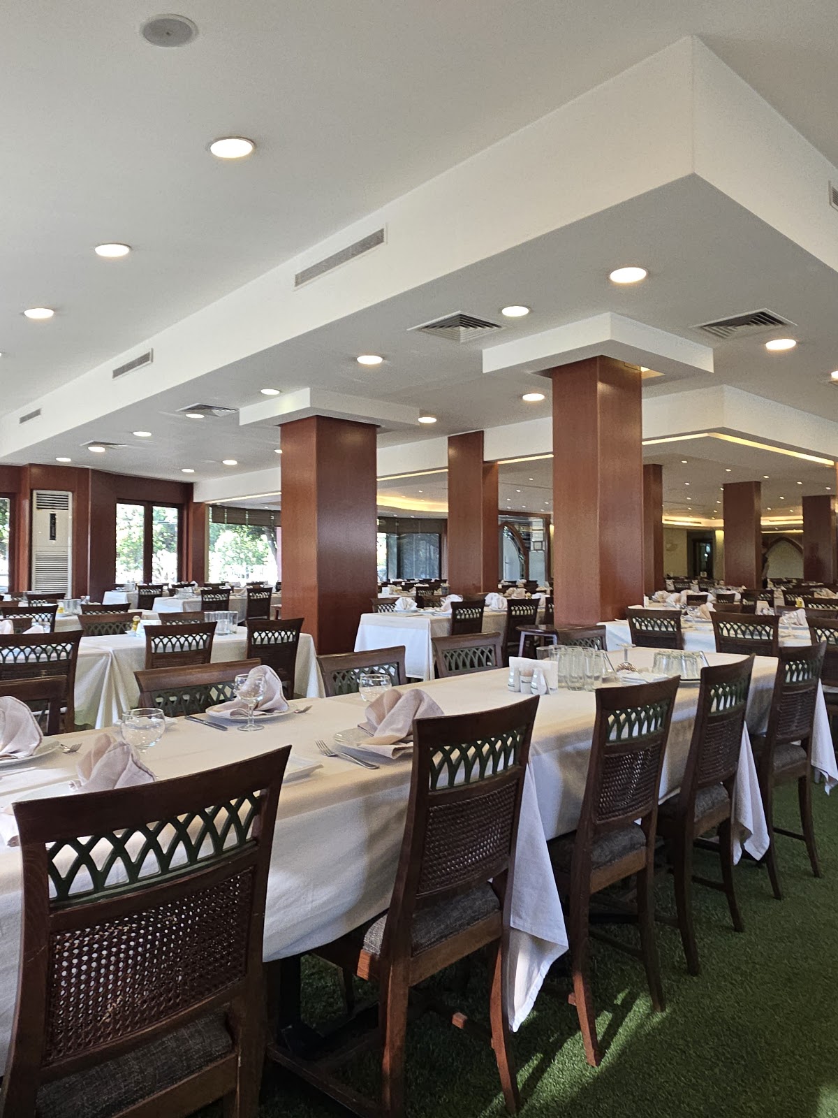 The banquet hall: wooden columns, long white tables set for service