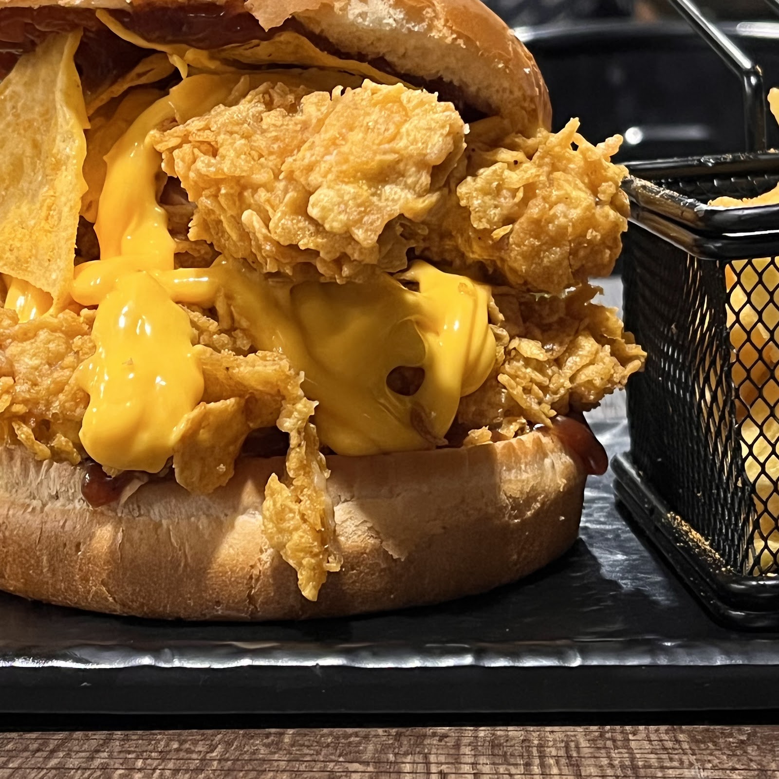 A zinger burger with crispy chicken and cheese sauce