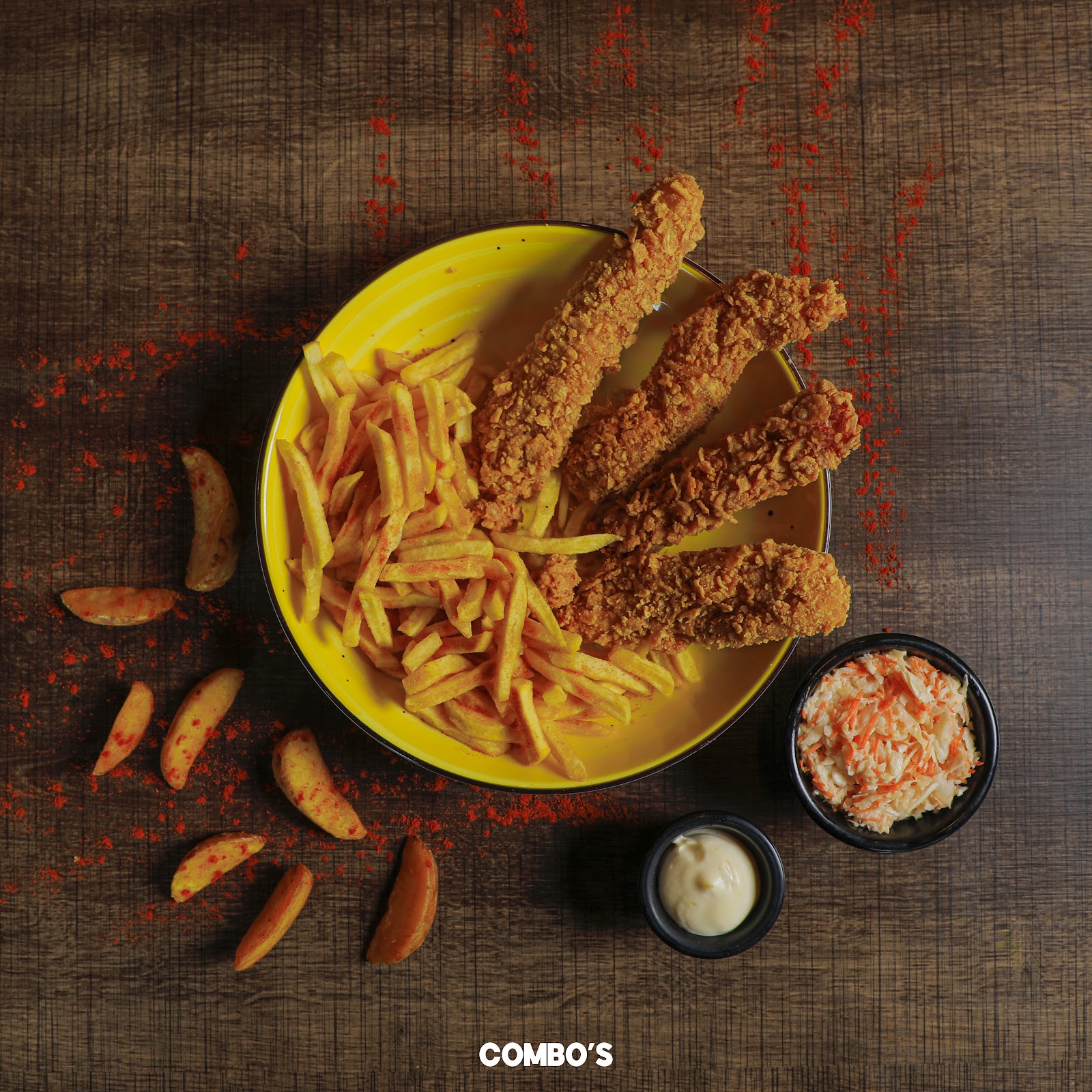 A yellow bowl of fries and tenders with slaw and sauce, from above