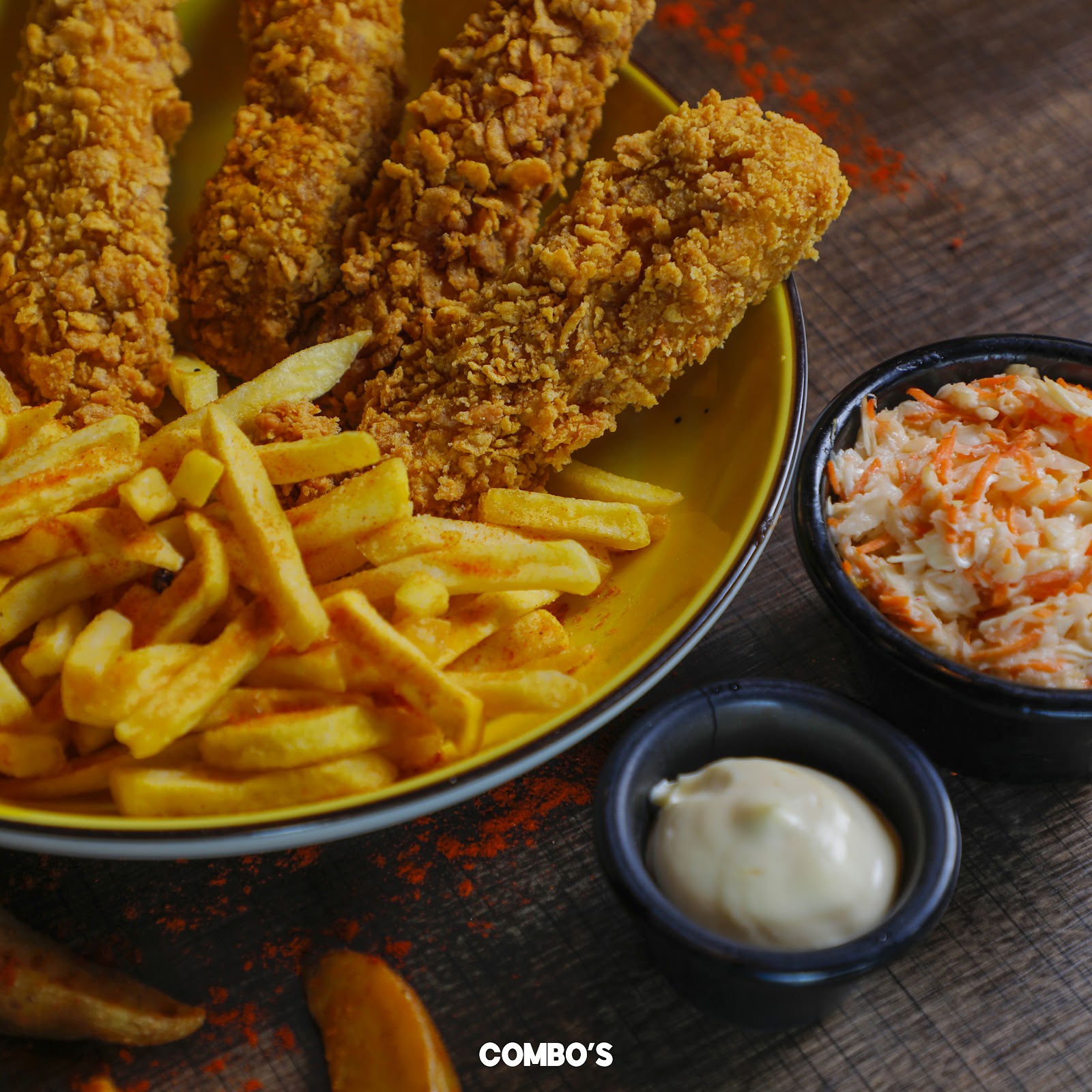 Crumbed tenders over a bowl of fries with slaw and a white dip