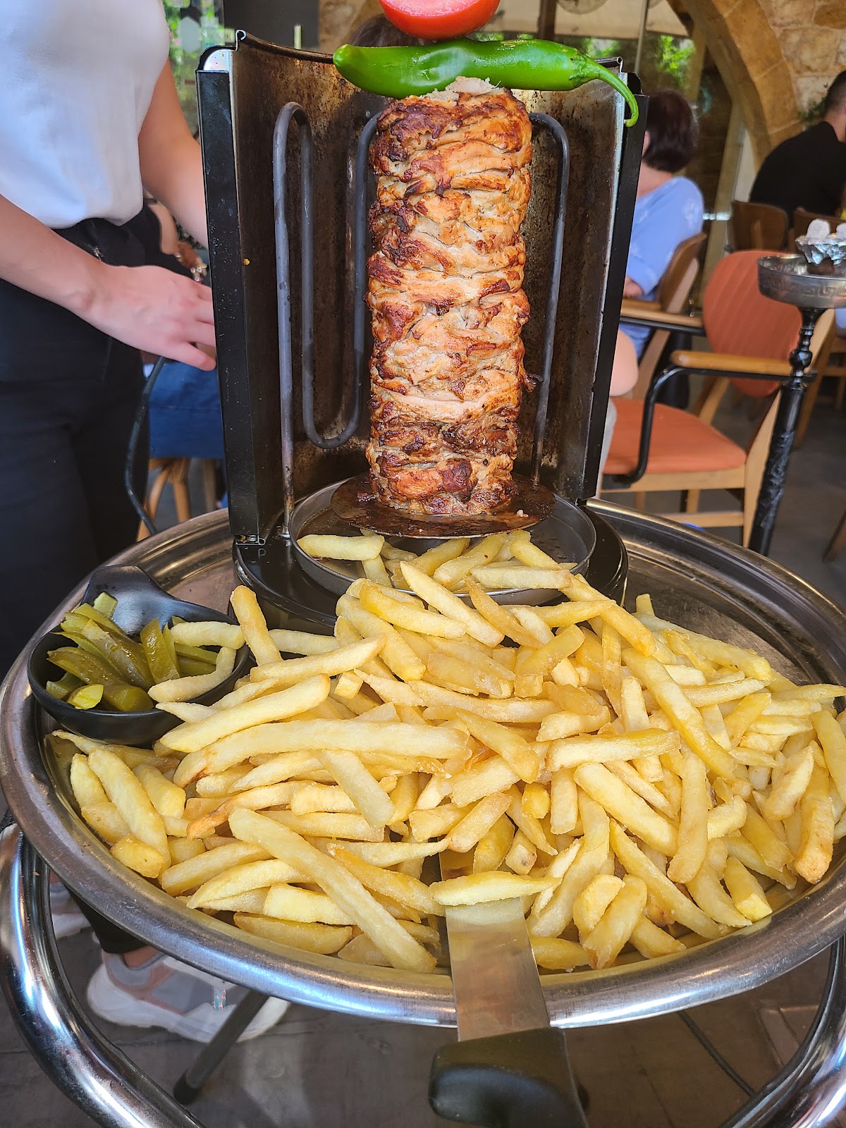 The chicken shawarma spit arriving over a tray of fries