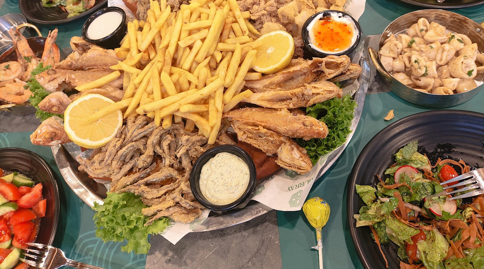 A Murray sharing platter from above: fried fish, calamari, whitebait and a mountain of fries, with salads and sauces around it