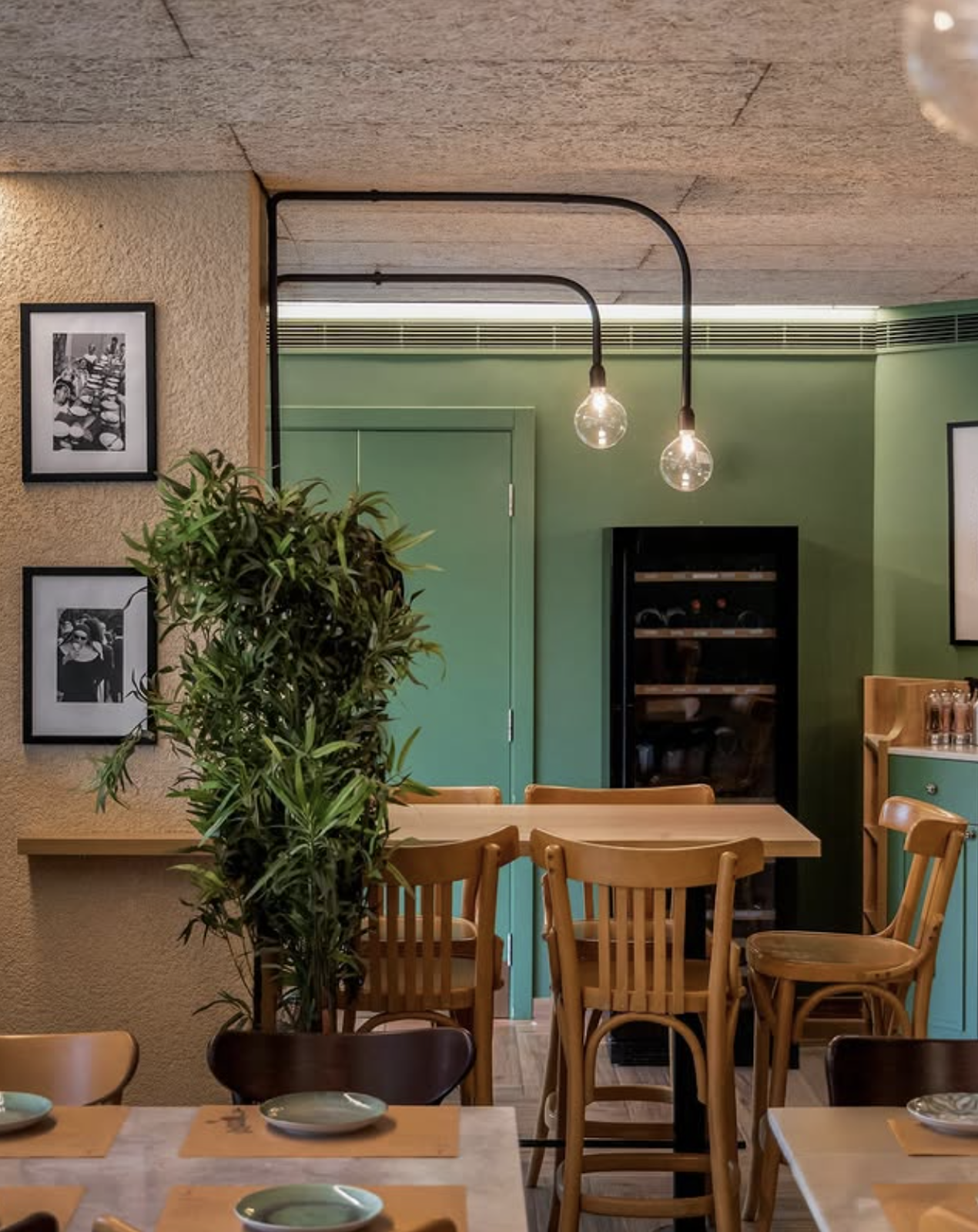 The mint-green dining room with framed photos and a plant