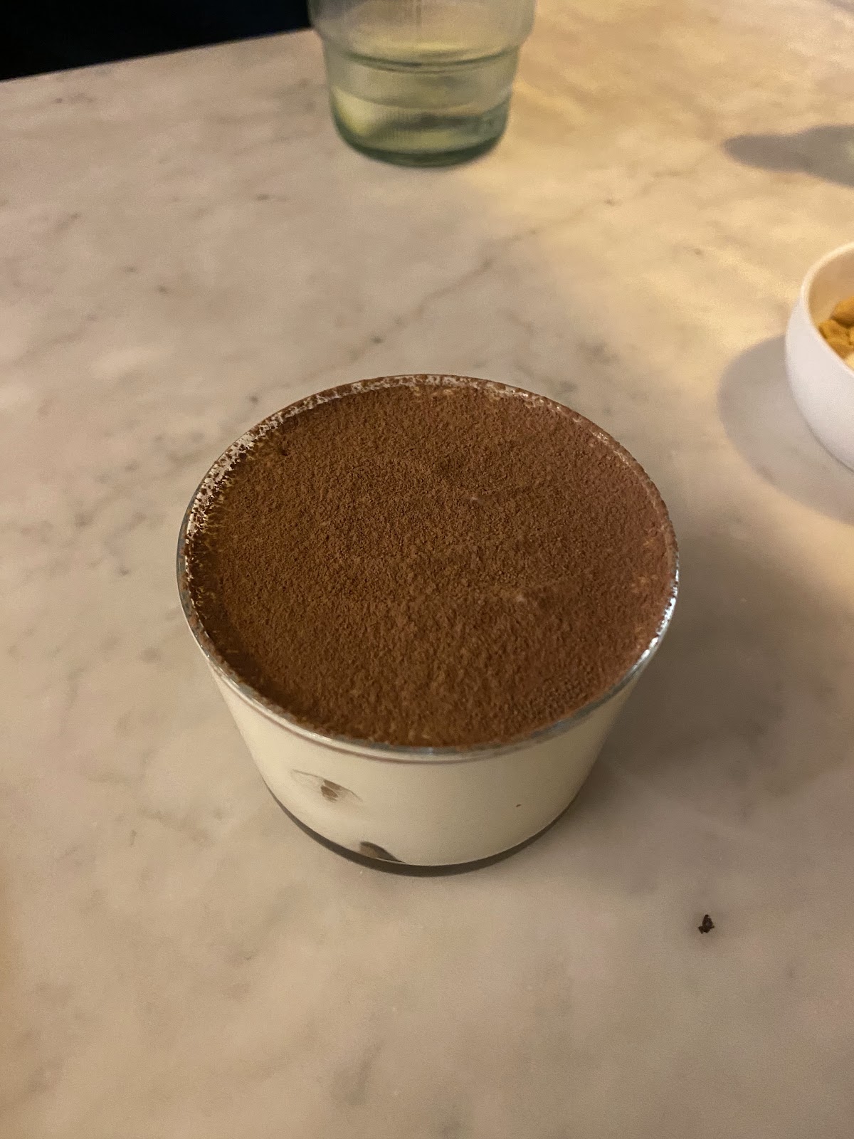 A cup of tiramisu dusted with cocoa on the marble table