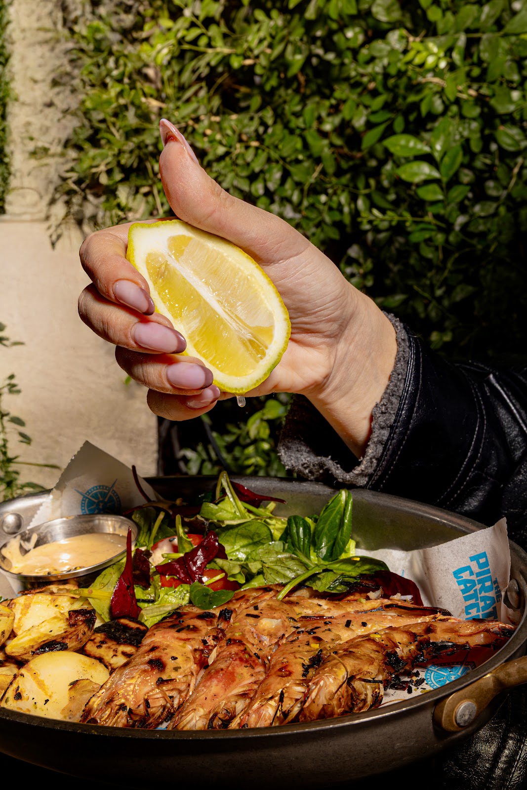 A hand squeezing lemon over a grilled fish plate